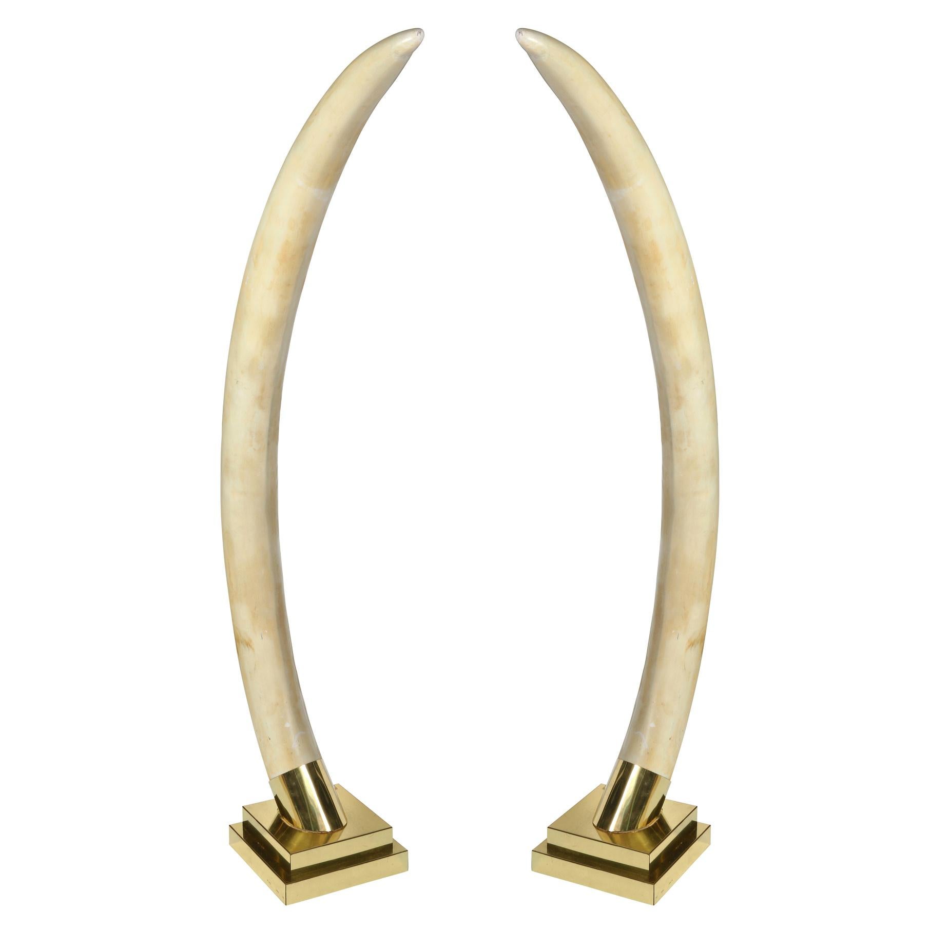 A pair of life size elephant tusks made of composition and mounted on metal bases. A show stopping conversation piece adds interest to any room.