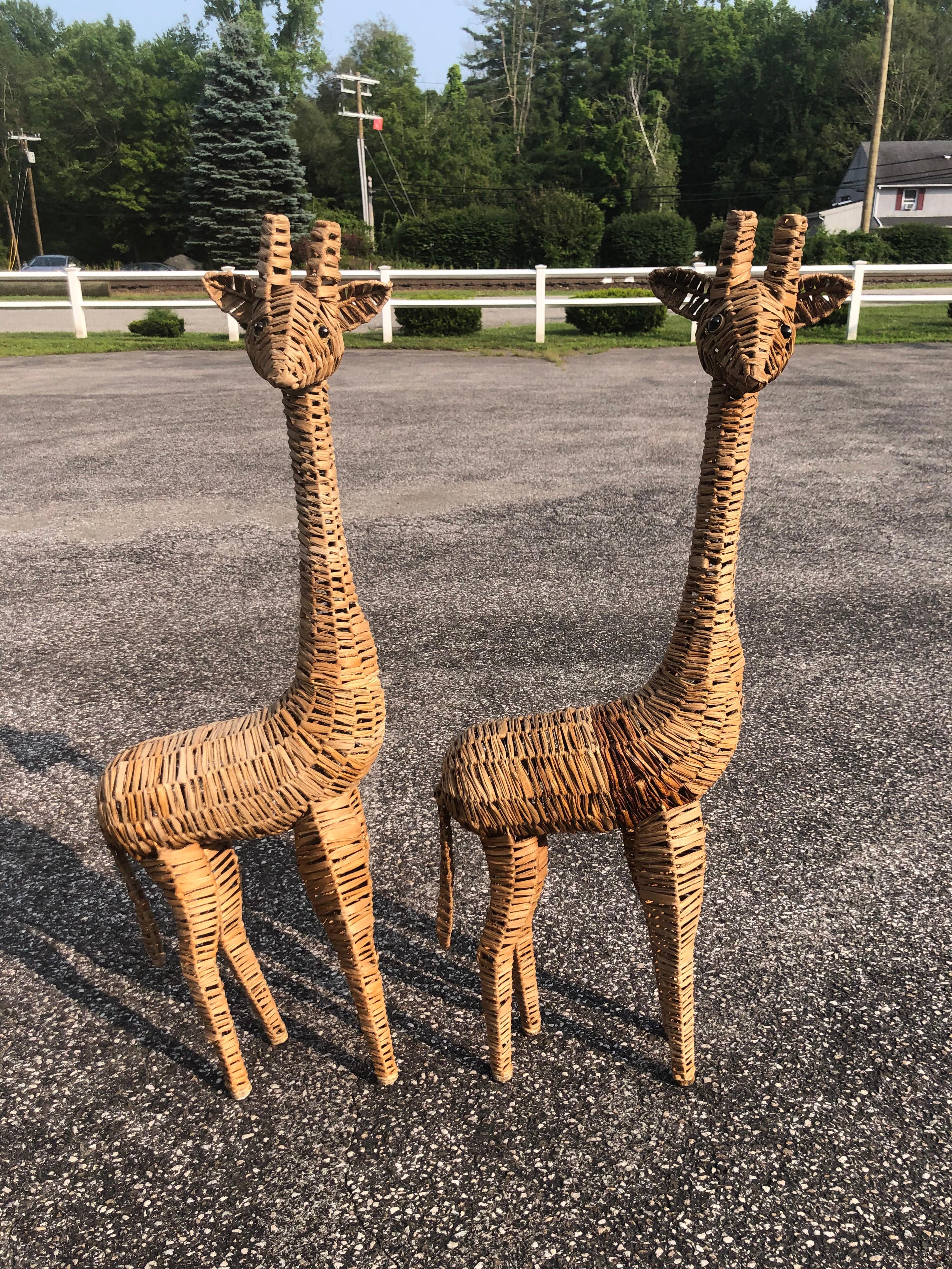 Pair of life-size woven giraffe statues. Weaved wicker with painted eyes. Fun, whimsical editions to any room, especially a child's. Boho chic In the style of Mario Lopez Torres.