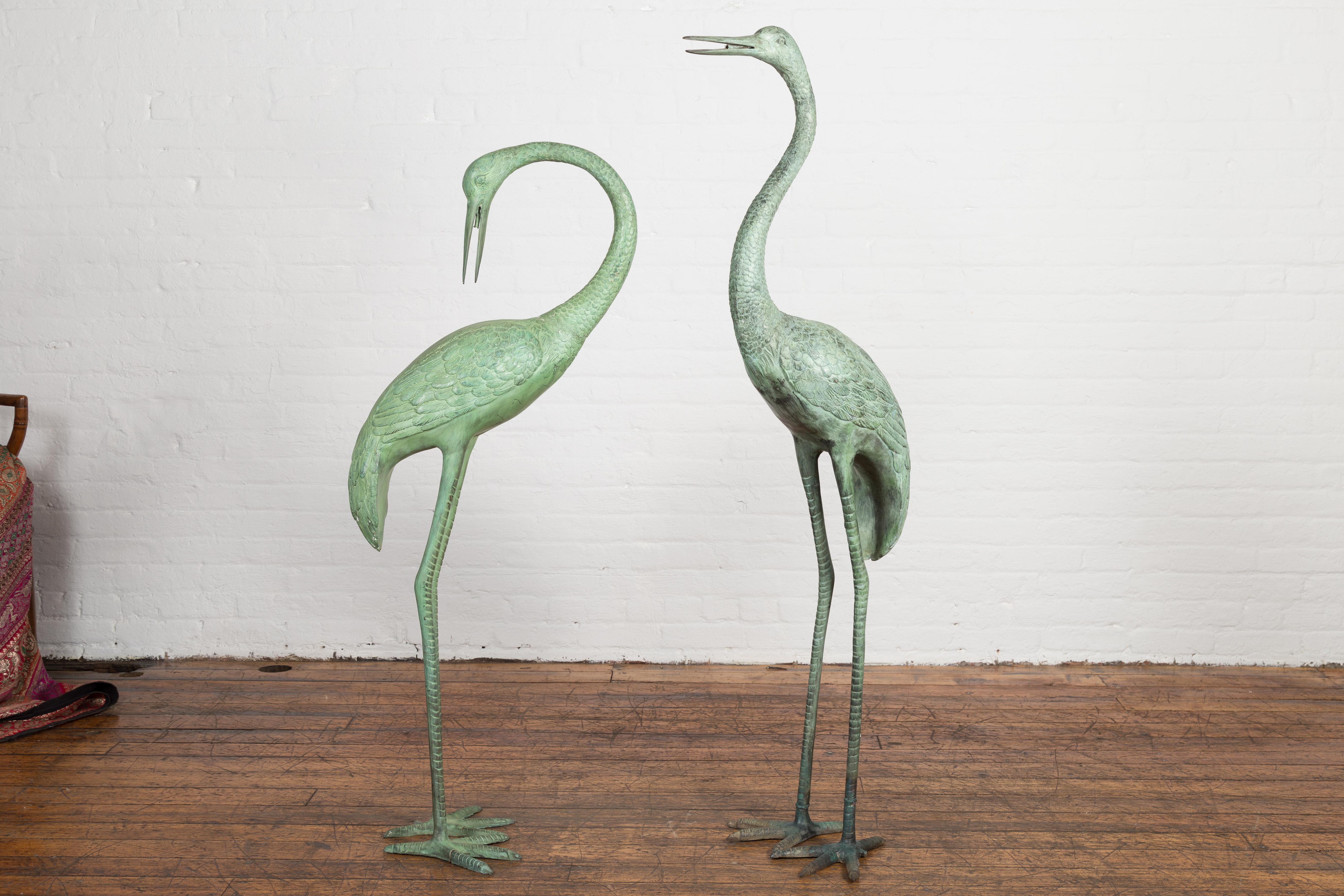 A pair of custom made lost wax cast bronze crane sculptures with verdigris patina, tubed as fountains. This is a current production, the ones in the photos are available now. This pair of custom-made lost wax cast bronze crane sculptures exudes an