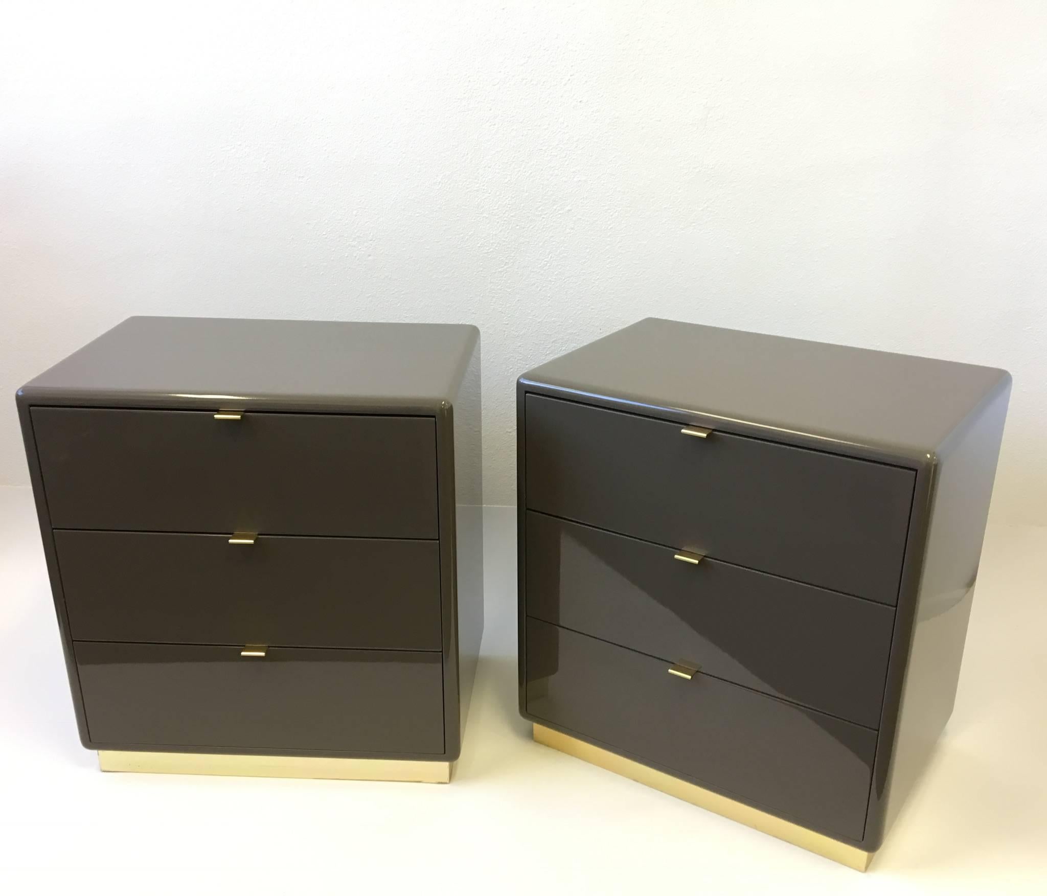 A beautiful pair of polish mocha brown lacquer with brass pulls and brass base nightstands. Each nightstand has three drawers. Designed by Steve Chase in the 1980s. 

Dimensions: 27