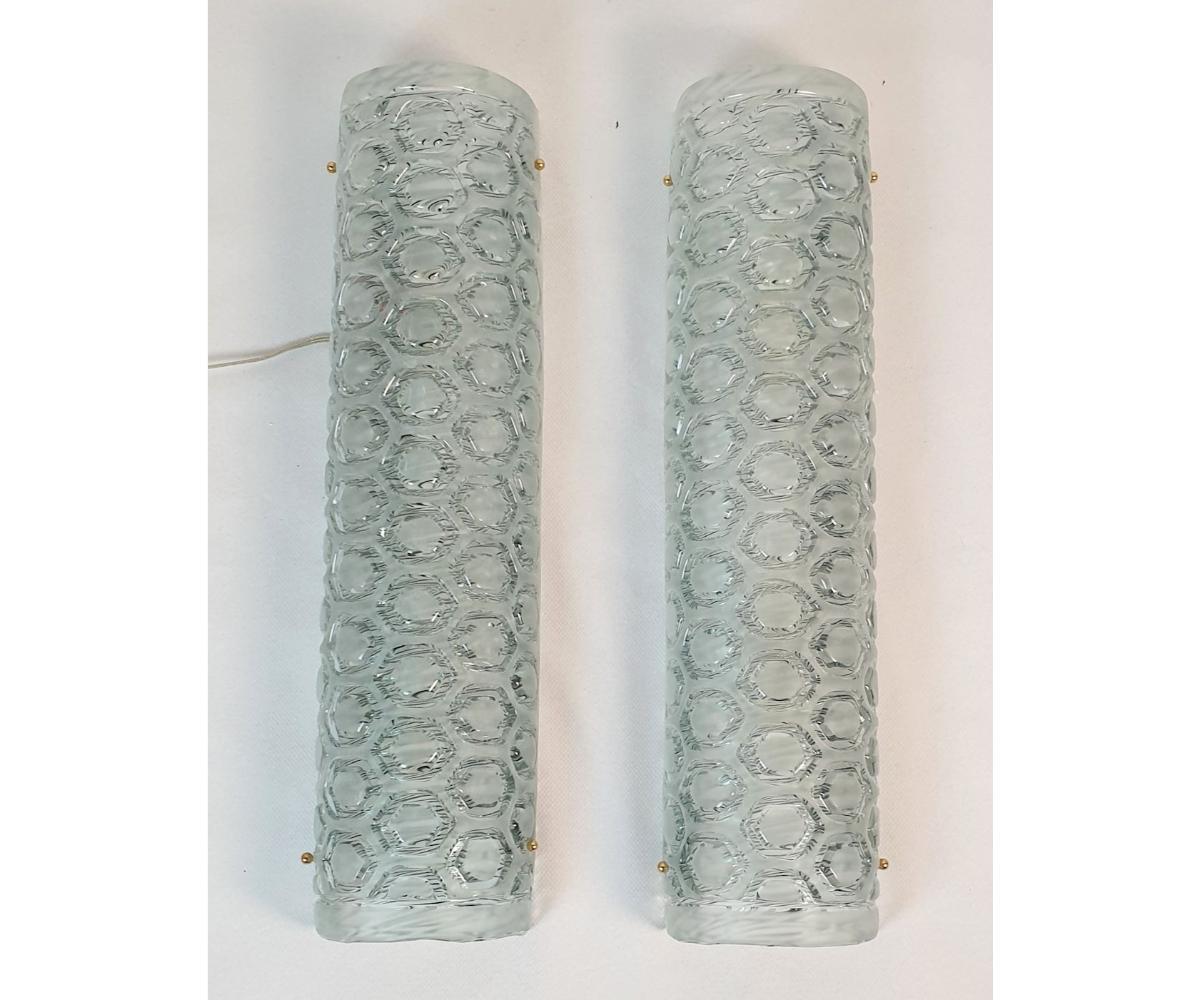 Pair of tall Mid Century Modern Murano glass wall sconces, attributed to Mazzega, Italy 1980s.
The vintage sconces are made of a light blue/green frosted Murano glass.
There is a nice medallion pattern showing the thickness of the glass, which is