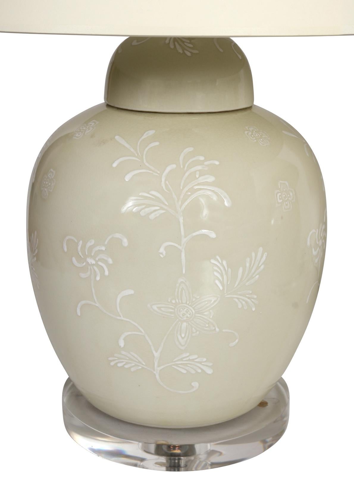 These urn shape lamps are neutral in tone, but the shape and lovely floral design throughout add dimension and detail. Their lucite base gives them a fresh, clean look. Lampshades not included.
