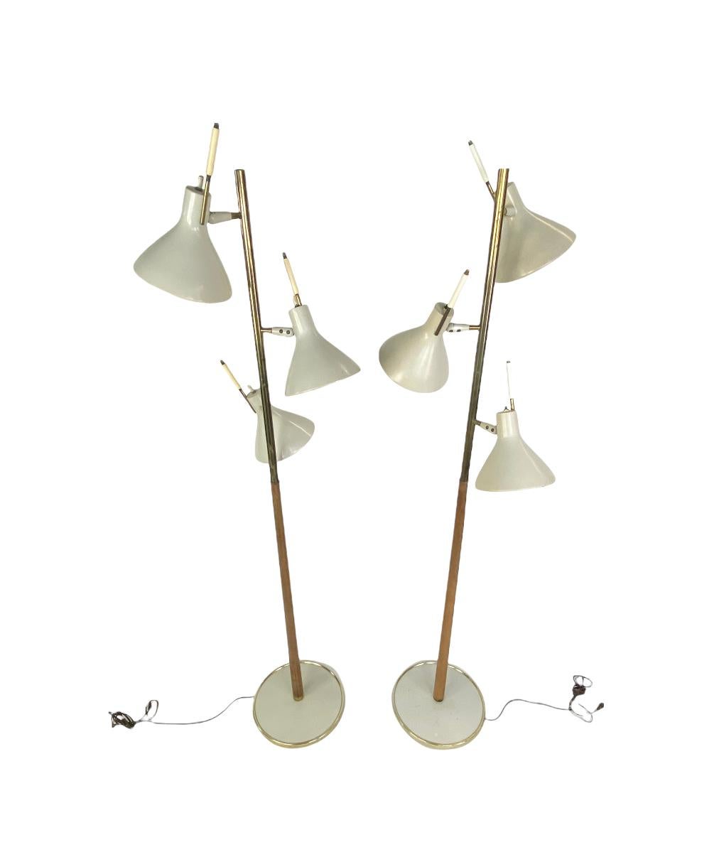 Handsome and elegant Midcentury floor lamps by Lightolier. Designed by Thomas Moser. Each with three pivoting shades, and all switches work. Executed with enameled shades, walnut pole, and brass trim. In good original condition.