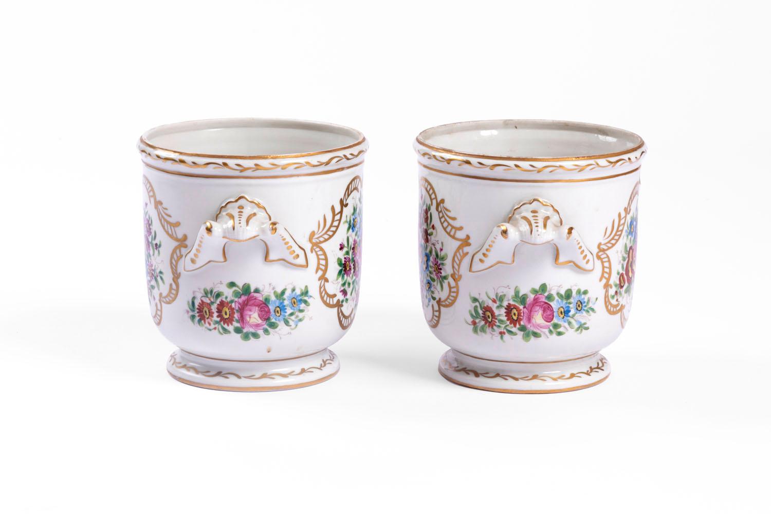 Pair of white background Limoges porcelain coolers. Polychrome enamel ornamentation representing flowers bouquets of roses, forget-me-not, blue and purple gerbera daisies, visible on each face of the coolers and in small size beneath the handles.