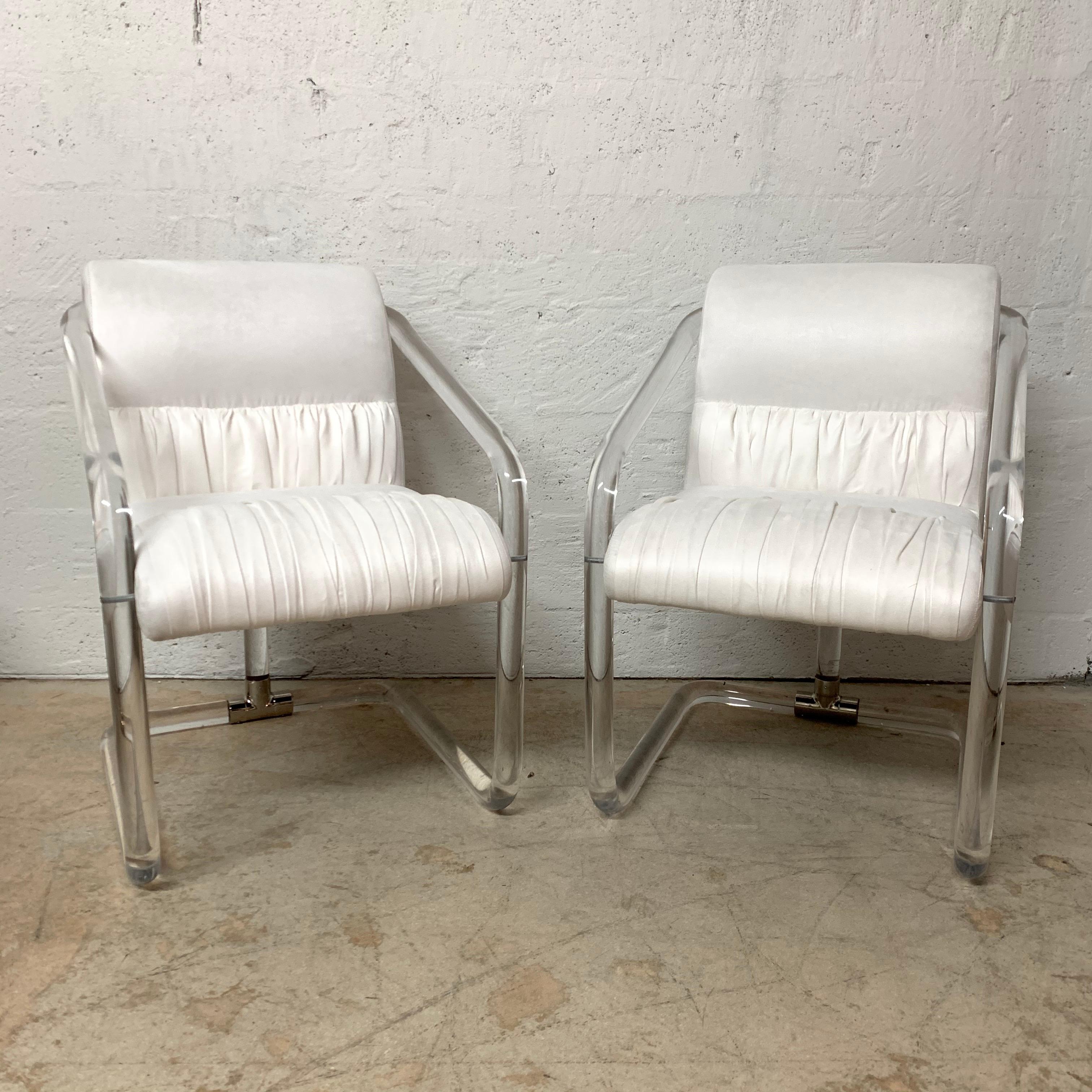 Versatile pair of chairs rendered in a bent tubular Lucite frame with nickel appointments and upholstered in creamy ivory white ultra suede fabric, signed, USA, 1970s.