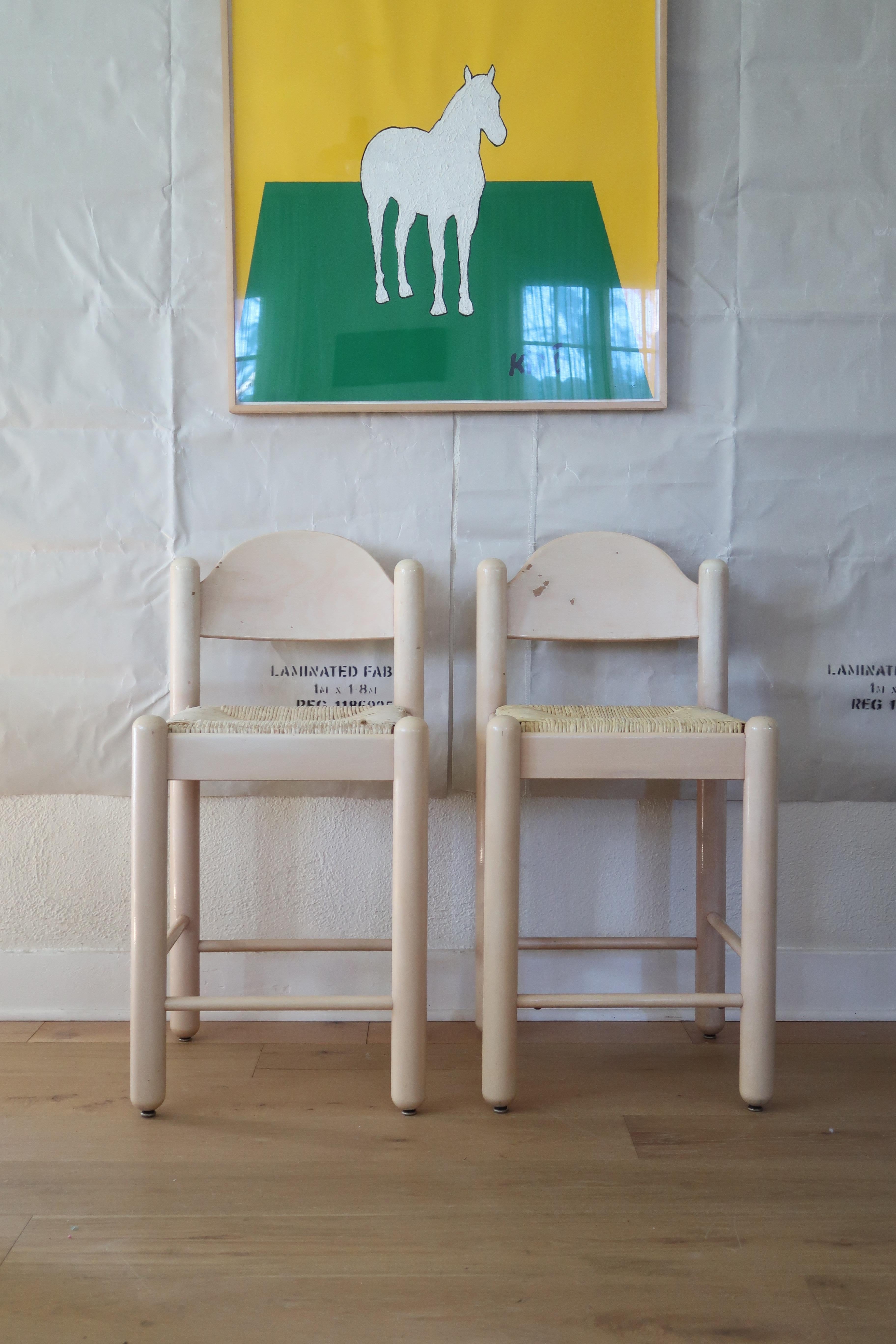 Postmoderne avec une touche de douceur. Cette paire de tabourets de comptoir de Loewenstein se caractérise par des pieds en goujon arrondis, des dossiers légèrement arqués et des sièges originaux en jonc tissé à la main qui permettent de garder les