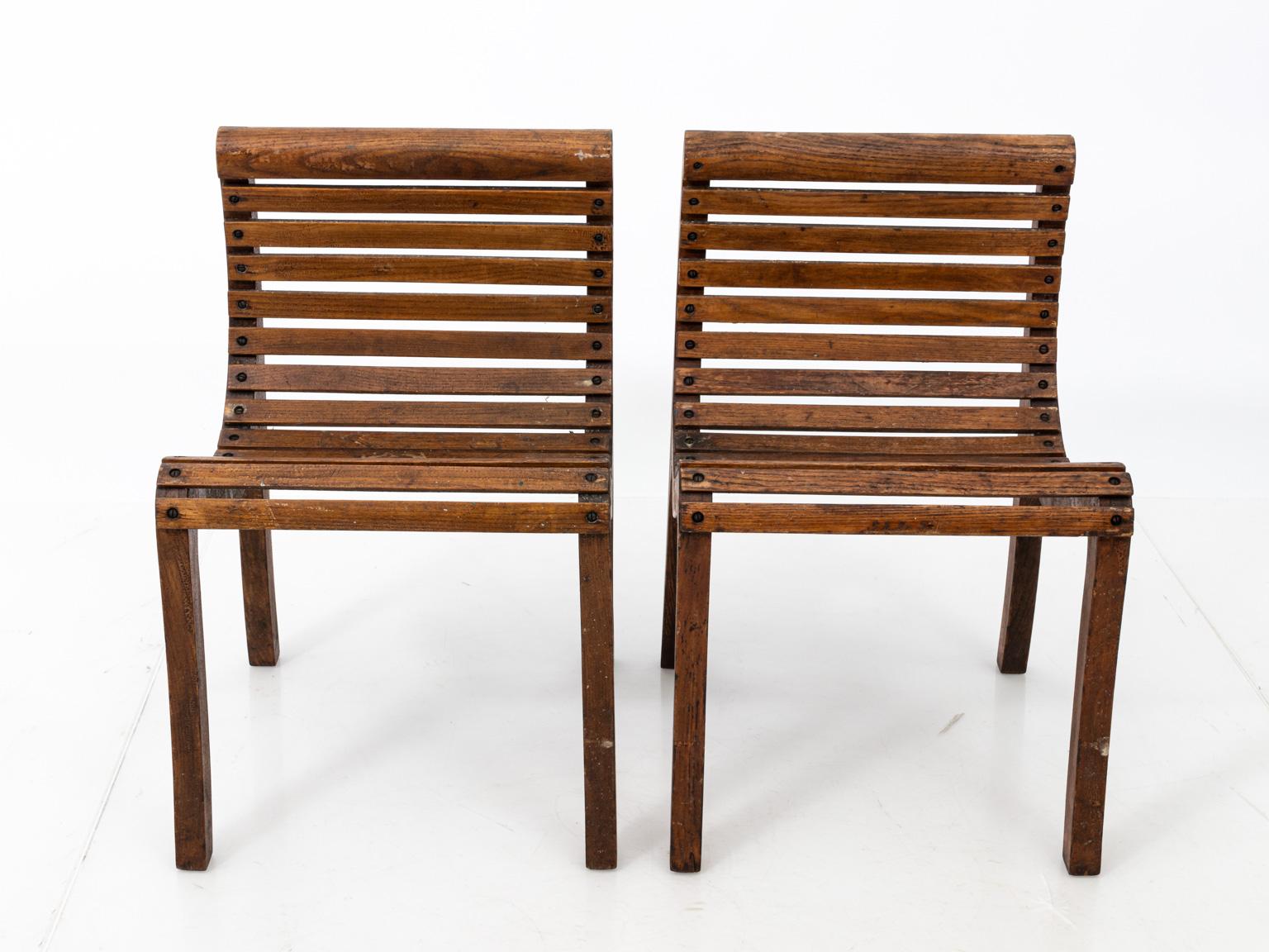 Pair of lolling oak chairs. Please note of wear consistent with age including finish loss and scratches, circa 20th century. There is also a maker's plaque that reads 