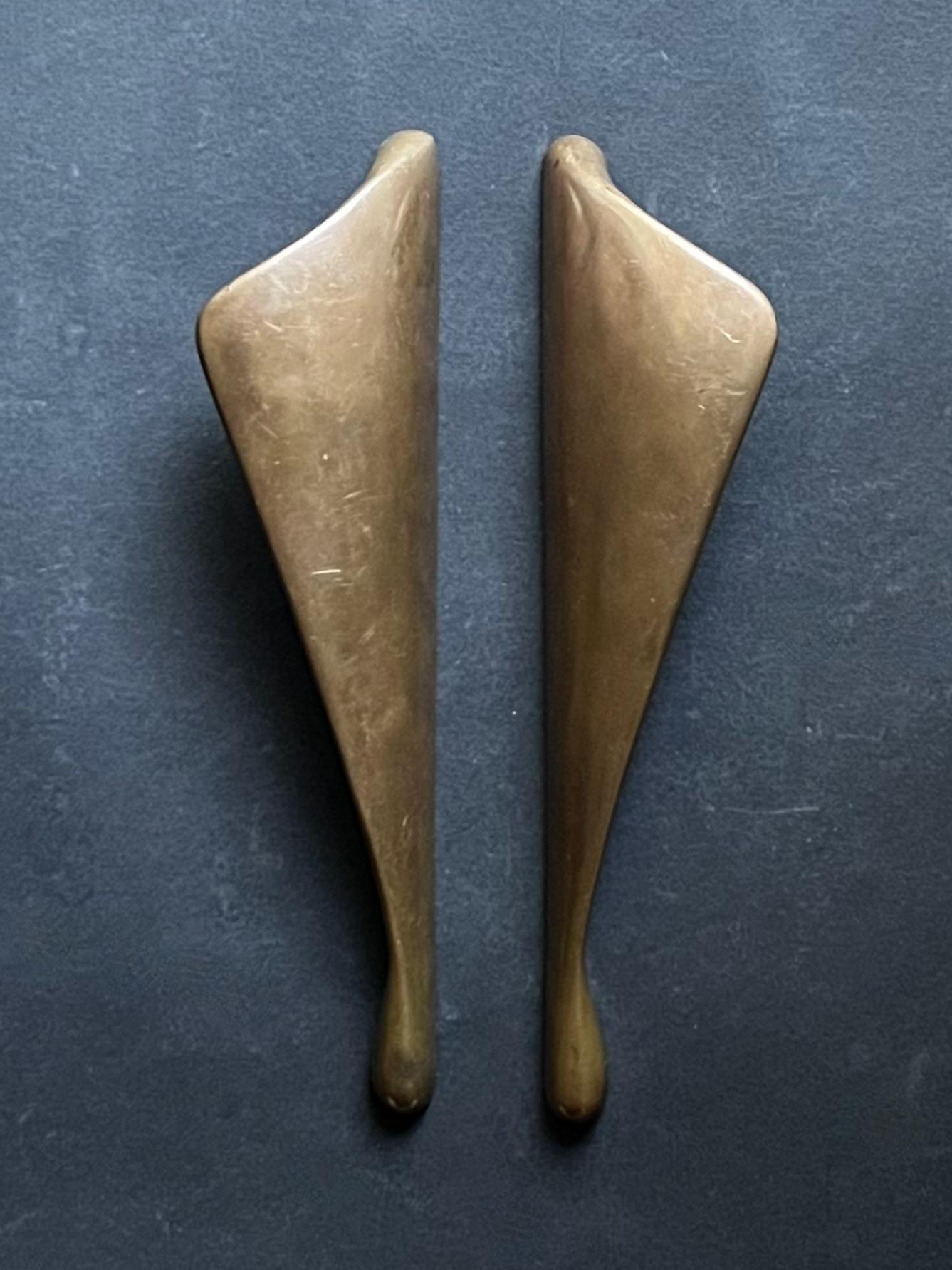 A pair of elegant push-pull door handles of cast bronze. 20th century, in art deco style. 

The handles have a tactile curved form - reminiscent of wings - and a warm mid-brown colour to the bronze, with red and gold tones showing in changing light.