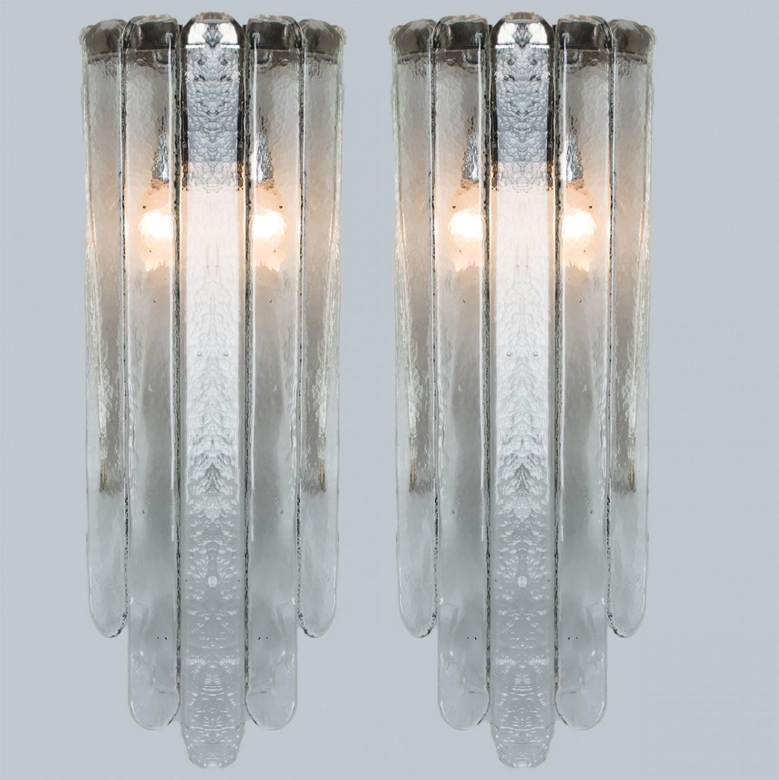 Pair of beautiful elongated wall lights, by Mazzega. A clear glass with the shape of a double pan-flute compose this beautiful piece made in thick handmade Murano glass.

Dimensions:
Height: 23.62