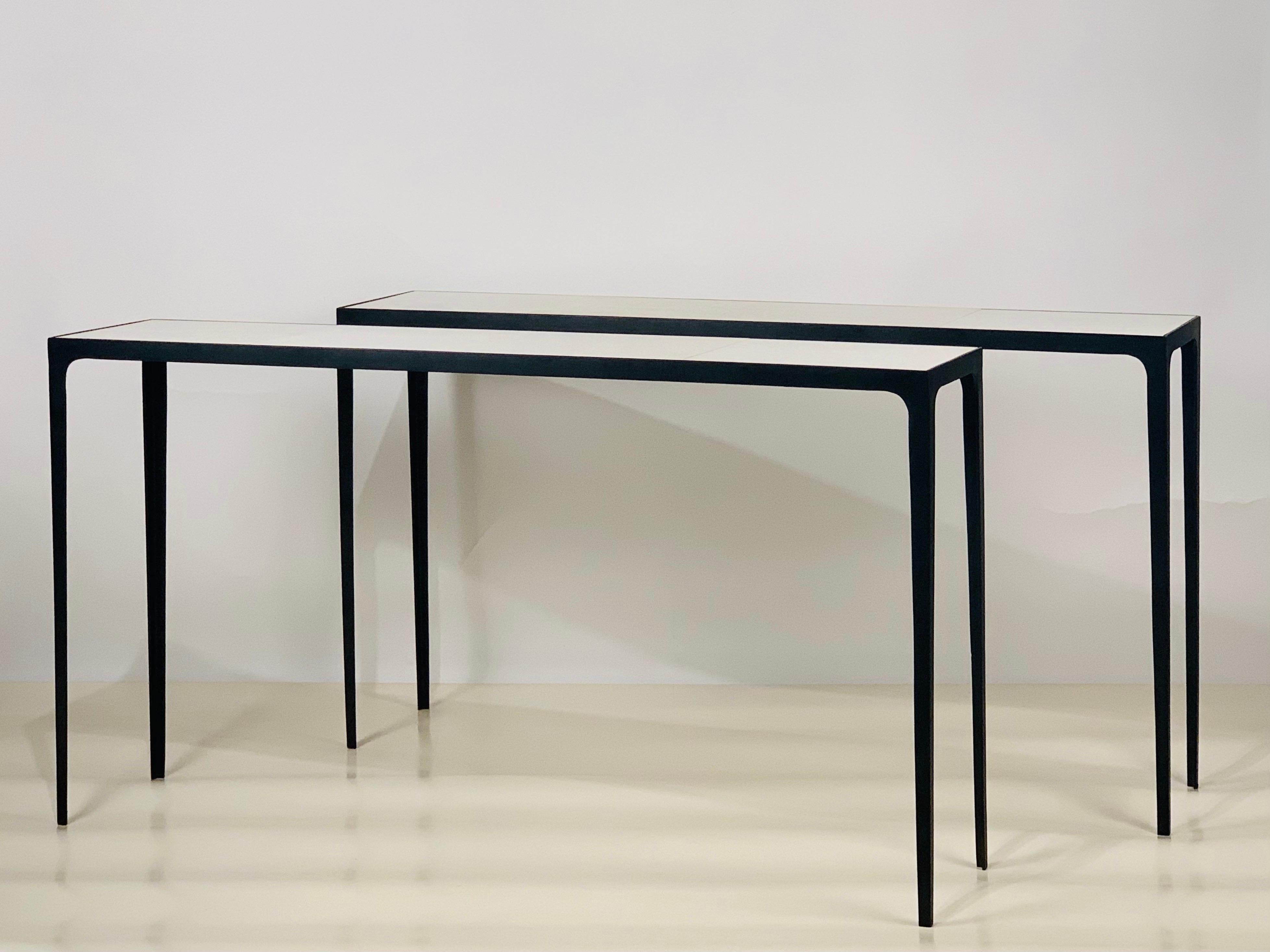 Pair of long 'Esquisse' blackened iron and parchment consoles from our exclusive Design Frères line.

Chic combination of slender blackened iron bases with inset goatskin (parchemin) clad tops.

Impressive proportions. Understated elegance.