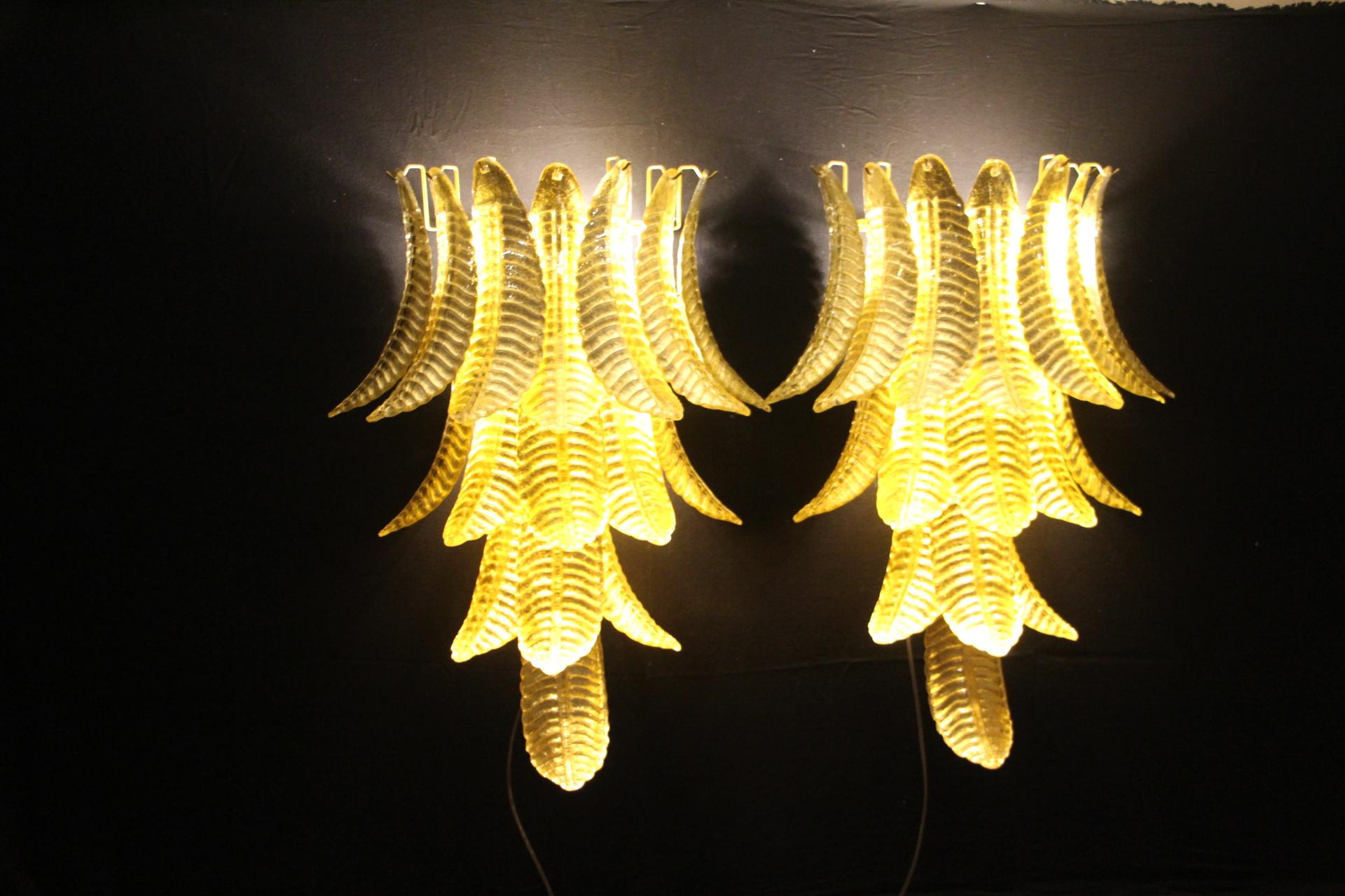 Este espectacular par de apliques largos se fabricó totalmente a mano en Murano. Cada hoja se fabricó individualmente en vidrio soplado de alta calidad, por eso podemos notar diferencias muy ligeras de una pieza a otra. Su color dorado se consiguió