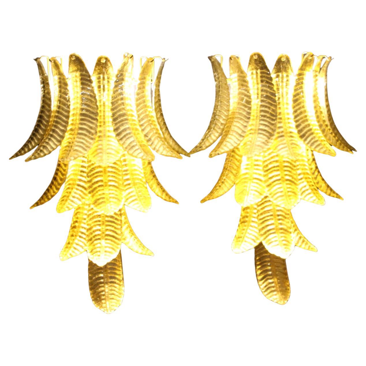 Questa spettacolare coppia di lampade da parete lunghe è stata realizzata interamente a mano a Murano. Ogni singola foglia è stata realizzata singolarmente in vetro soffiato di alta qualità, per questo motivo si possono notare leggerissime