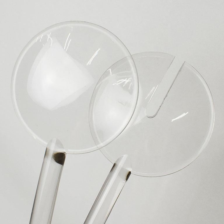 A pair of Lucite or acrylic salad serving utensils. One is a spoon, and the other for salad. The tops of each are circular, and the long handles are round. This would be a great addition to a holiday or special occasion table. Age-appropriate wear