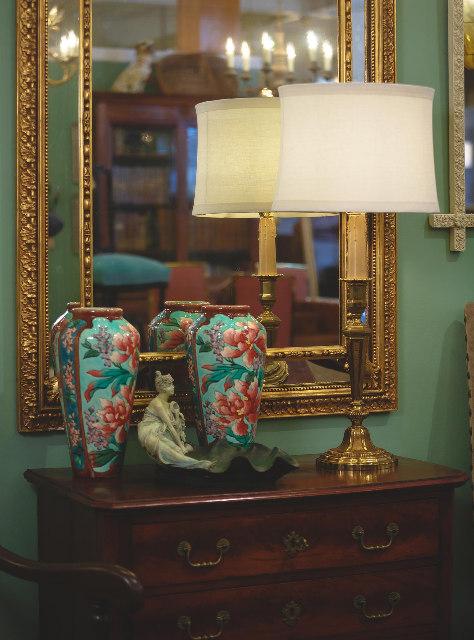 A vibrant pair of ceramic vases with colorful flowers from Longchamp Barbotine, circa 1900. Two tall vases with simple rims, high and sloping shoulders, and body that tapers towards the base. The single low vase has the same general shape, but