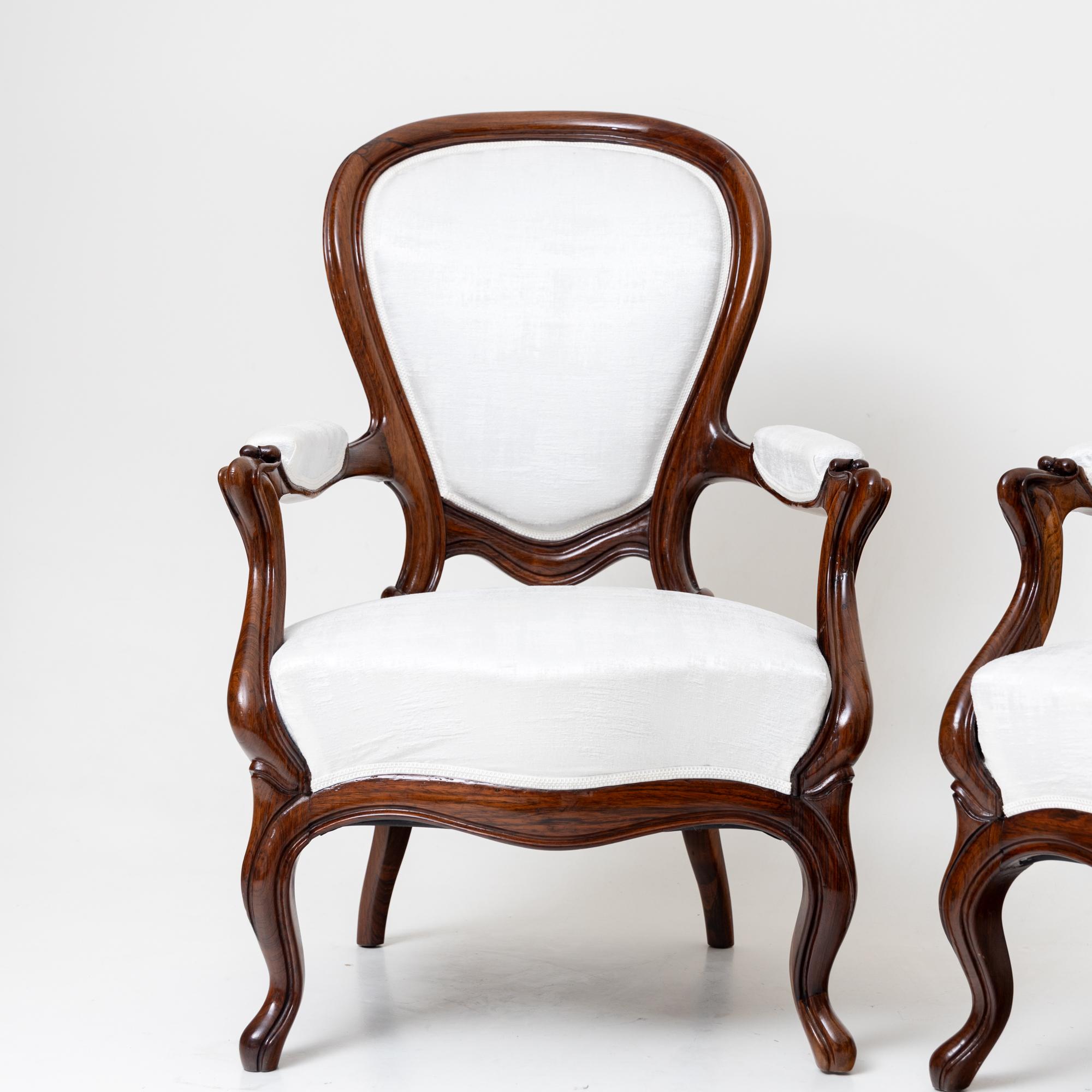 Pair of Louis Philippe armchairs on s-shaped curved legs with an elegant wavy frame and upholstered armrests. The balloon-shaped backrest and the seat and armrests are upholstered in a textured white fabric. These chairs have been carefully