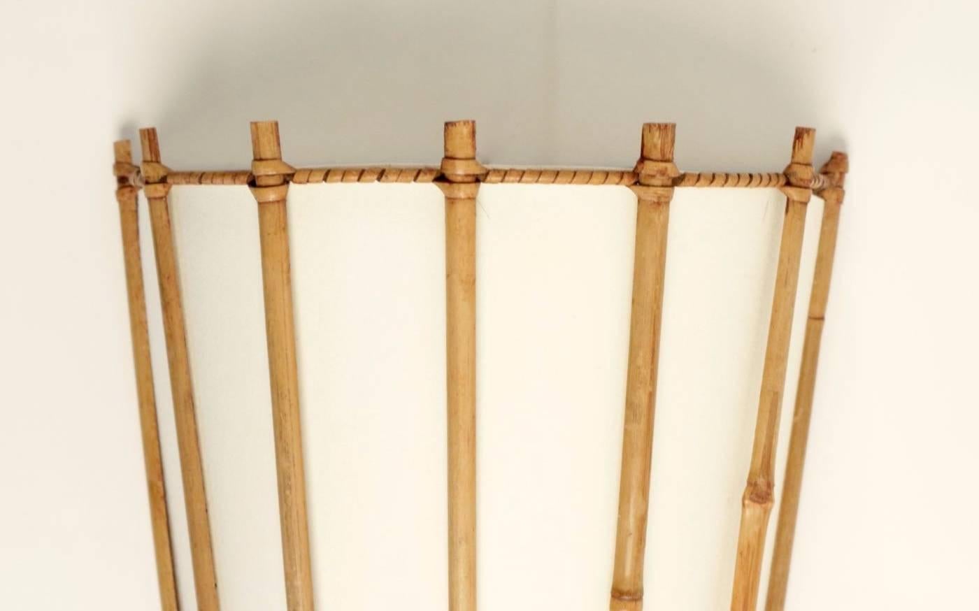 Pair of Louis Sognot bamboo and rattan sconces, 1959.

Consists of a half cylinder made of bamboo stems tied with rattan.
Lampshade made of off-white cotton, granted to the original.

One bulb per sconce. 
Can be rewired to US standards.