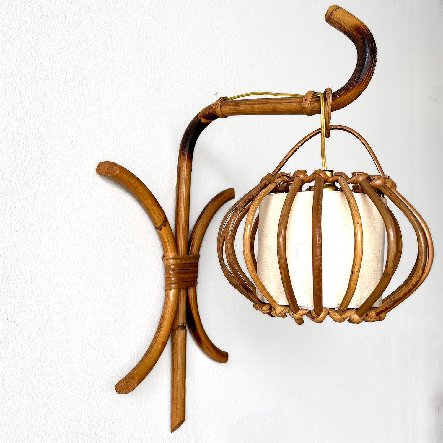 Pair of Louis Sognot “lantern” sconces
France, circa 1960’s 
Sculptural rattan ascending arm holds a delicate rattan lantern shade 
Original shade lining shows signs of age
Composed of natural materials
Each lamp is unique in its