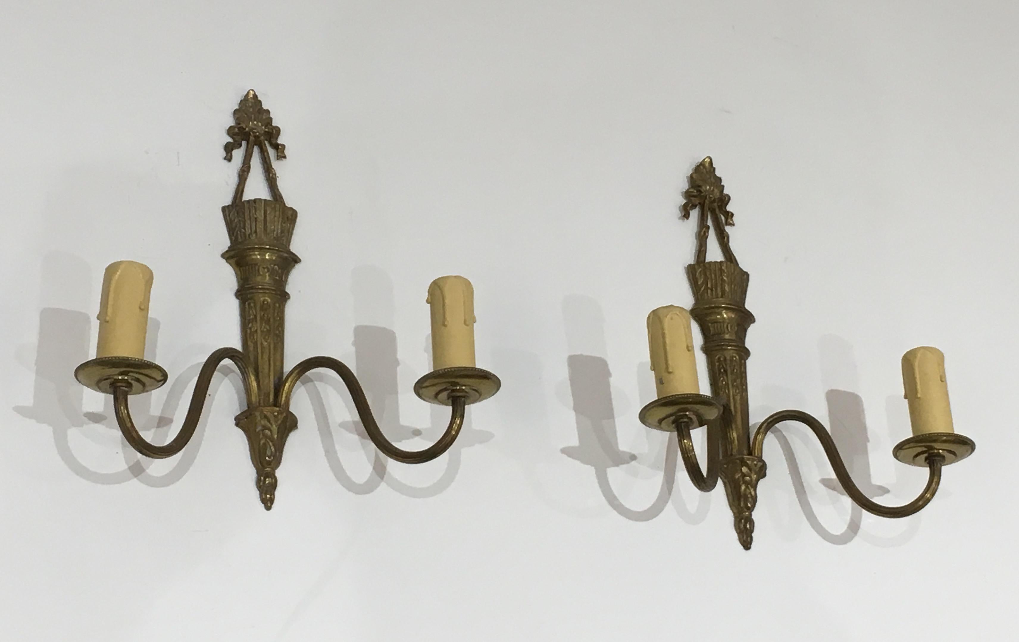 This pair of wall sconces is made of bronze. These sconces are in the style of Louis the 16th with quiver and ribbons. This is a French work, circa 1960.