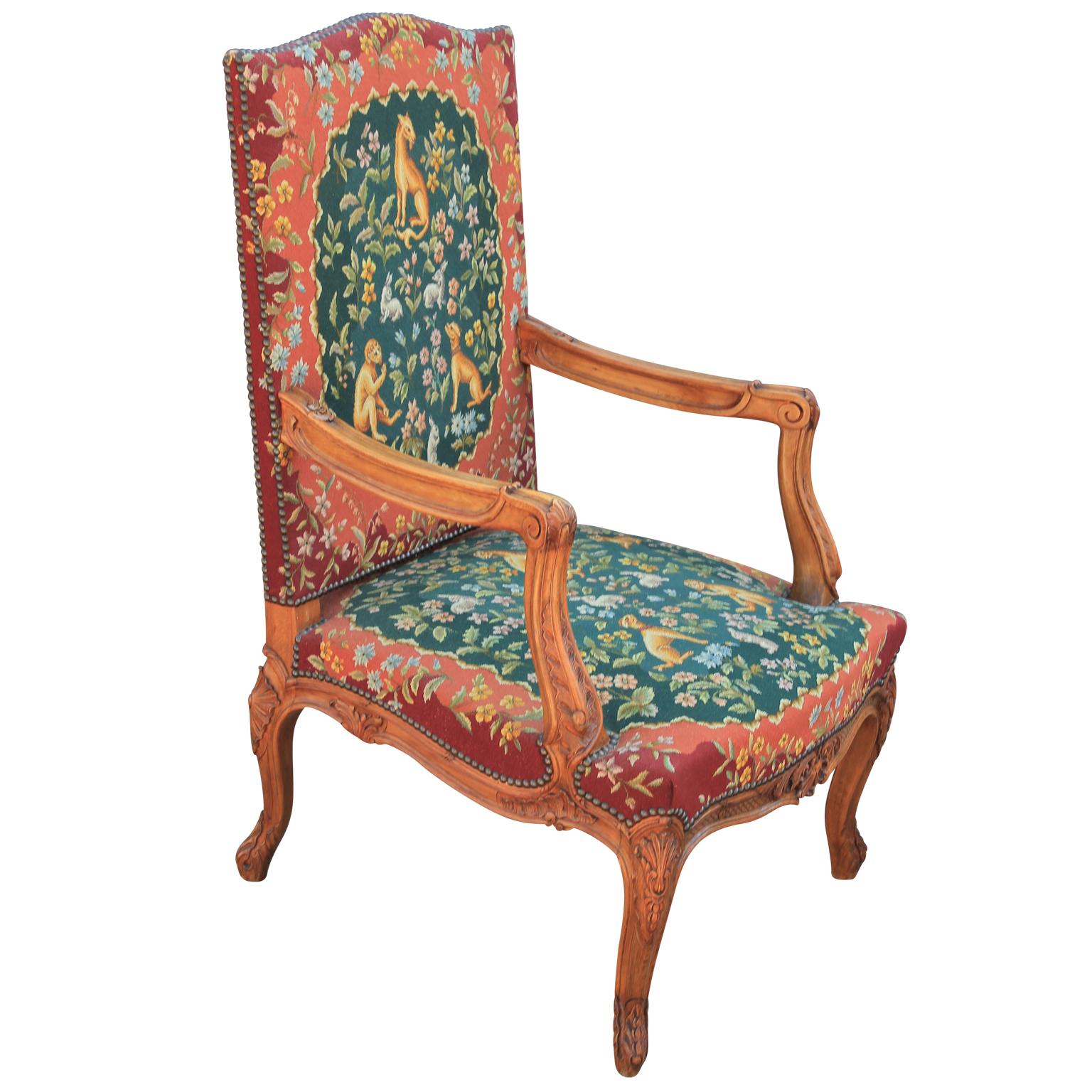 Exquisite pair of Louis XIV needlepoint upholstered walnut armchairs, shaped crest with open scroll arms, over cabriole legs ending in beautifully carved feet. Upholstered with an 18th century style intricate needlework depicting a variety of exotic