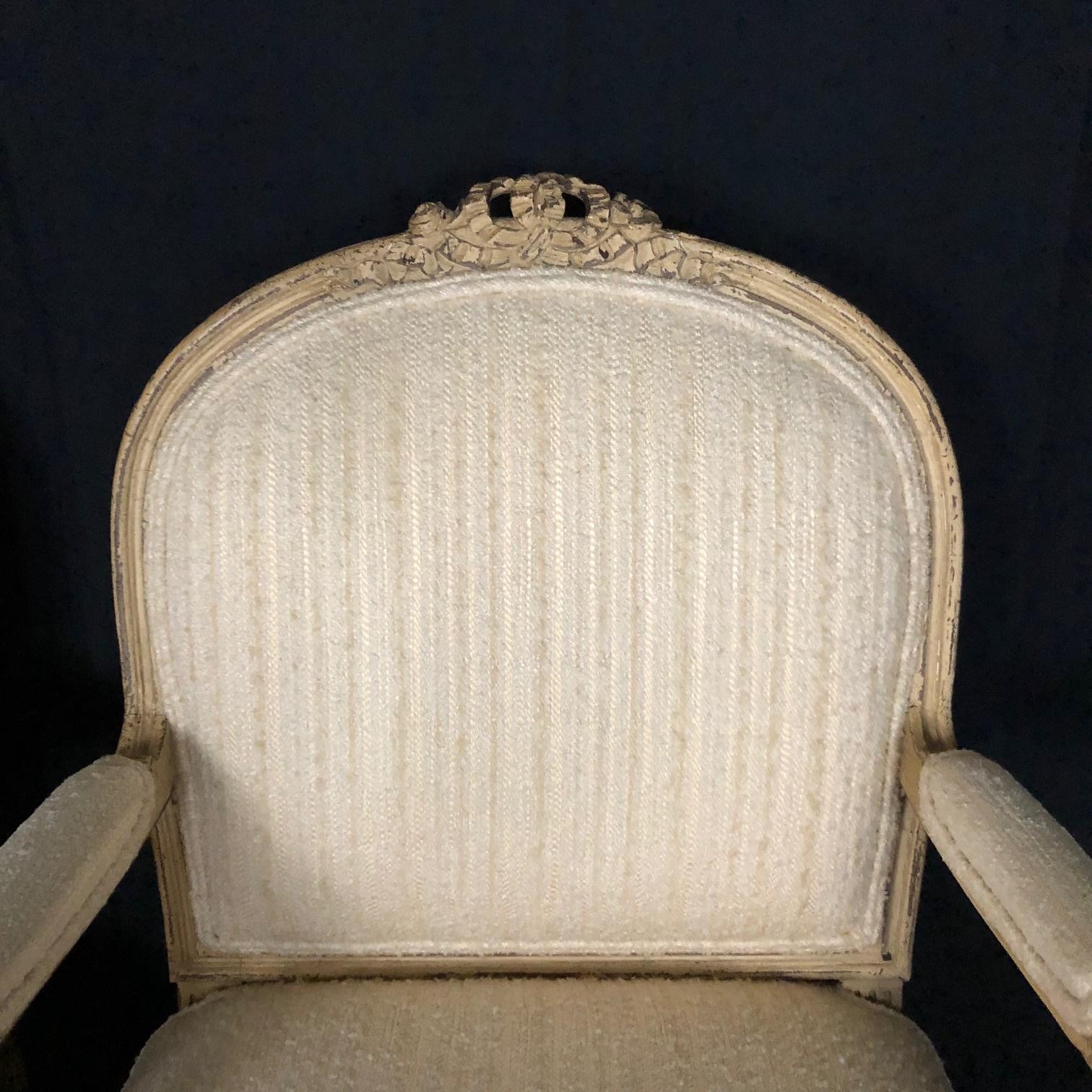 Pair of exquisite painted French bergère armchairs with ivory and cream paint and complementary upholstery, circa 1940s. Measure: Arm height 25.5
#5248.