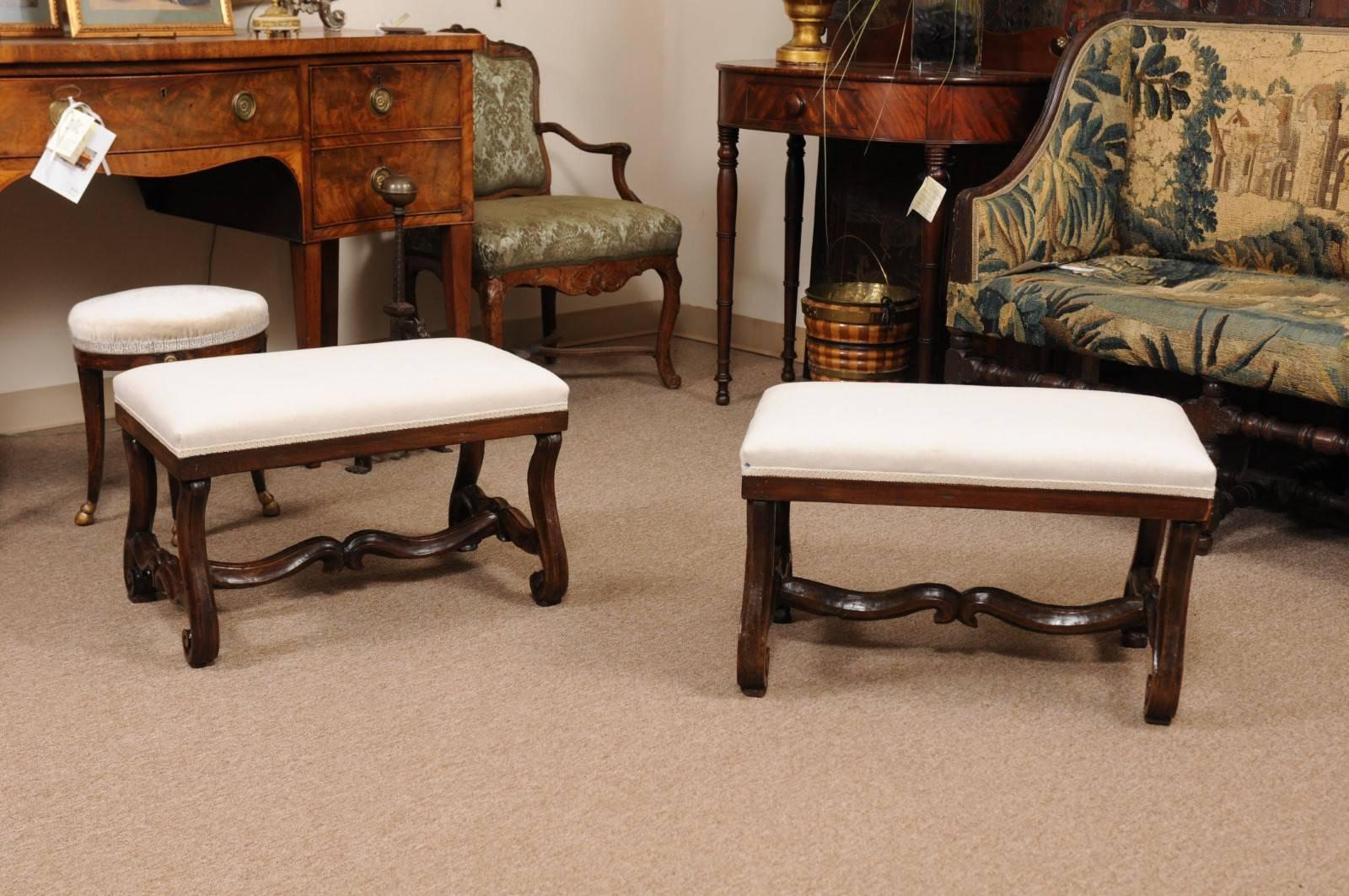 The pair of 18th century Italian walnut benches with linen upholstered seats and carved 