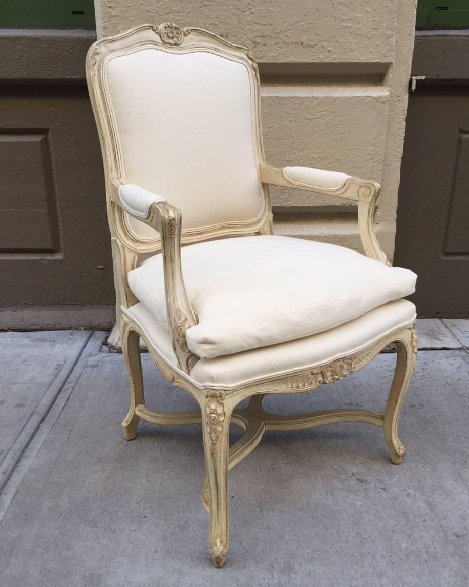 Pair of Louis XIV style armchairs. The chairs have a painted wood, carved frame with an off-white upholstered fabric.
  