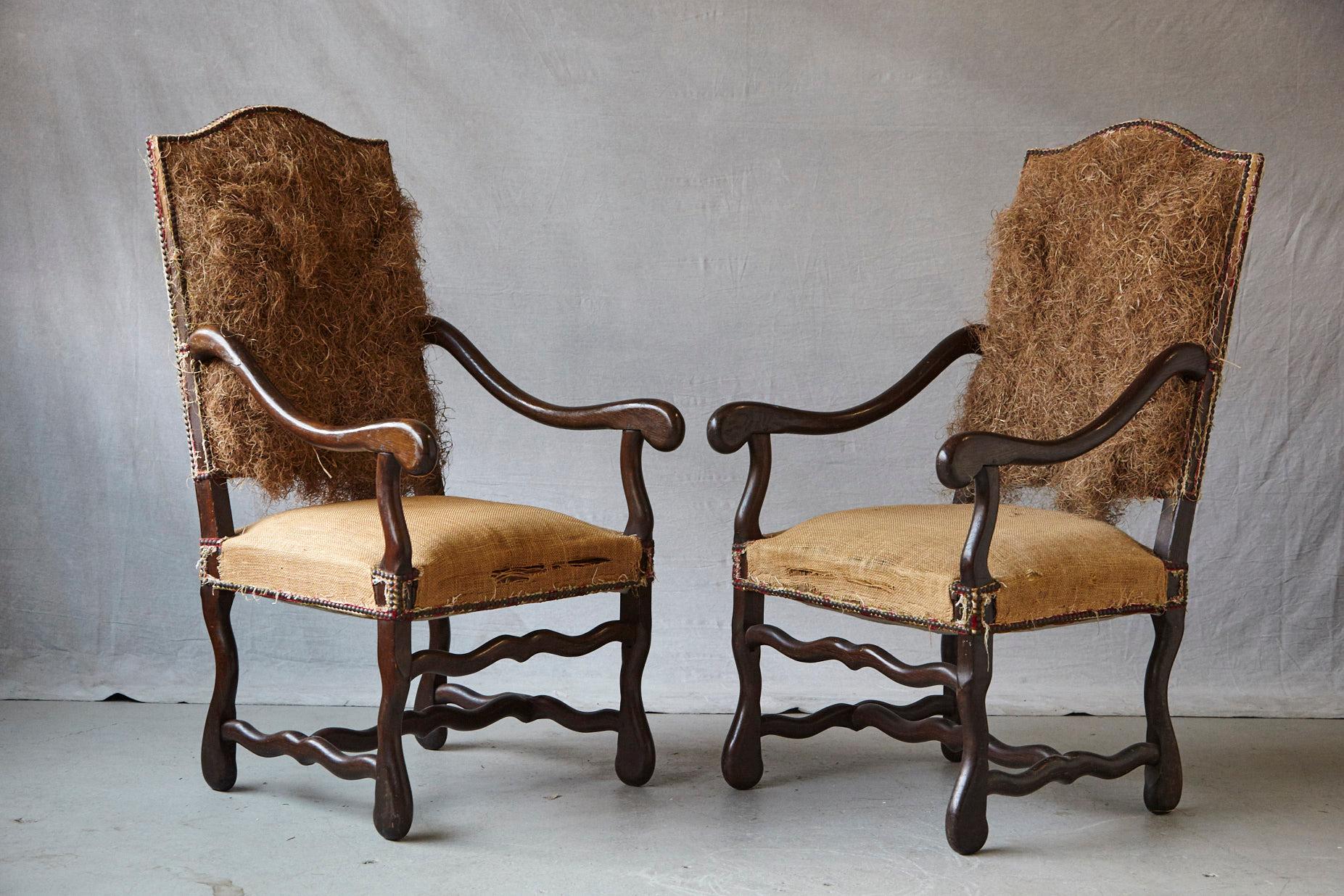 Unusual pair of Louis XIV style, Os de Mouton, walnut fauteuils restyled into this particular look by Michael Trapp, with removed upholstery, seat and rear covered in burlap, nailhead trim and exposed straw filling.

The fauteuils were acquired in