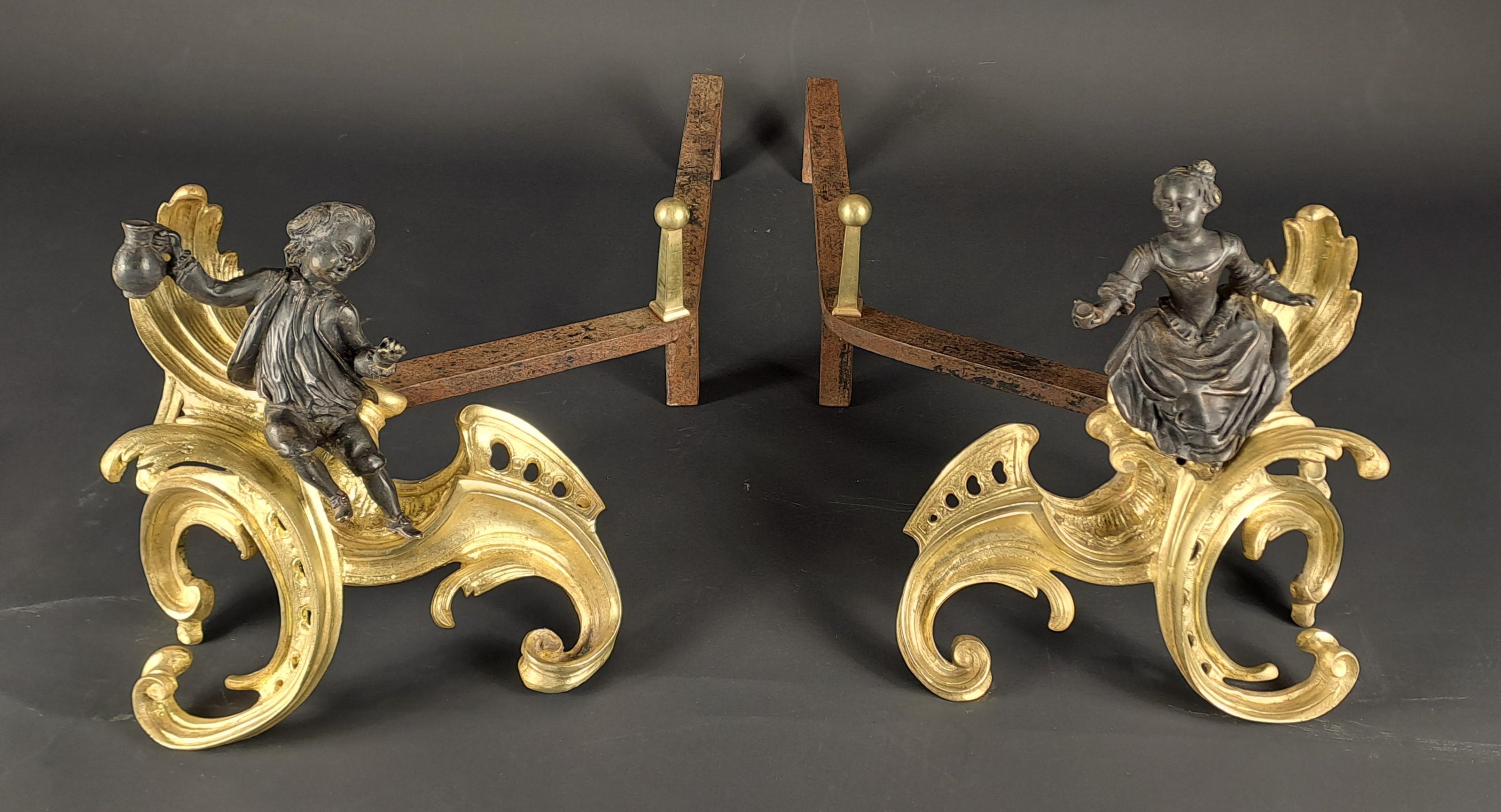 Pareja de morillos de bronce con doble pátina que representan a una pareja de personajes en postura festiva, mostrando una jarra de vino y una copa, en una decoración rocaille de hojas de acanto y volutas.

Obra francesa del periodo Luis XV.

Buen