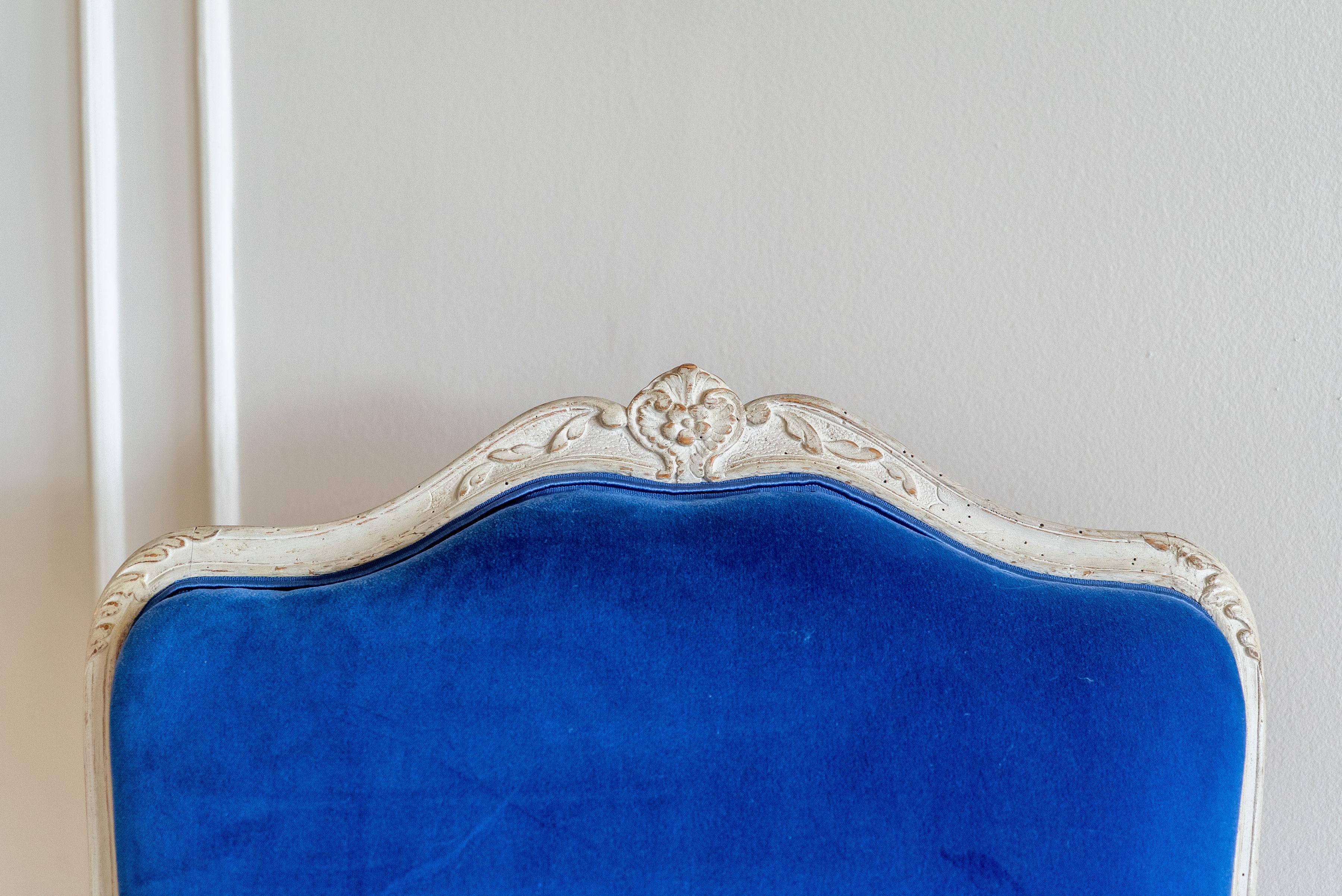 Elegante coppia di poltrone bergère in stile Luigi XV, del XVIII secolo circa, con struttura in legno intagliato e dipinto. Rivestito in pelle scamosciata blu reale sui sedili e sui braccioli. Le sedie emanano un comfort lussuoso e un audace