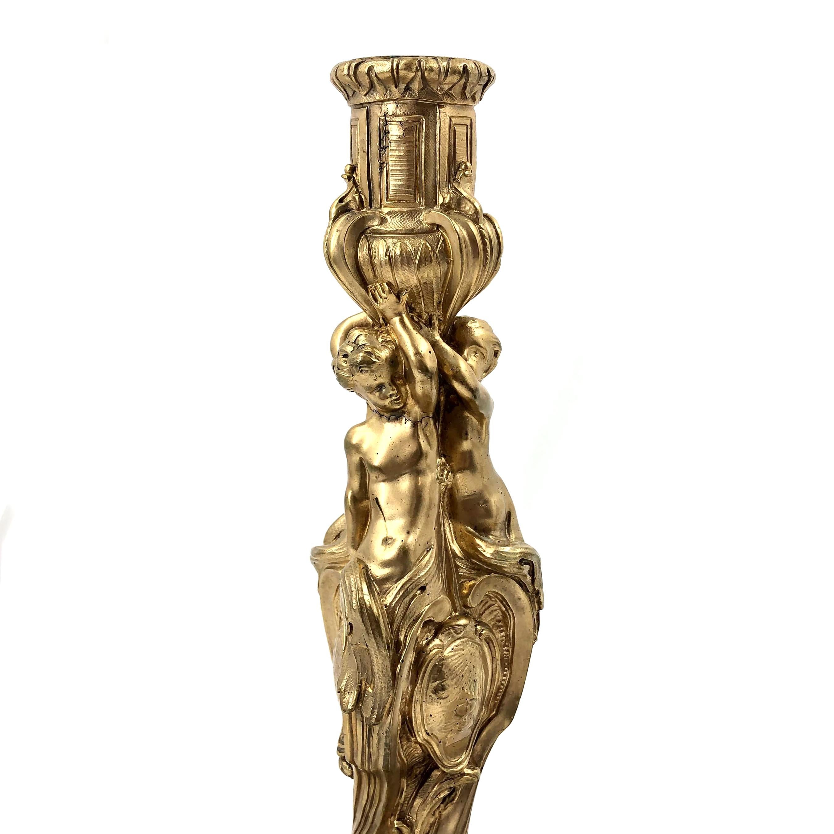A fine pair of French Louis XV gilt bronze figural candlesticks in the manner of Meissonier. Beautifully decorated and chased with leaves and two Putti perched on the stem holding the cup above their heads.