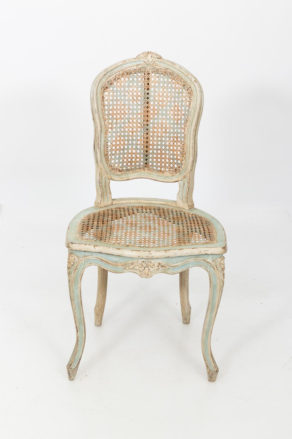 Pair of painted Louis XV style woven cane back side chairs with blue lattice stencil work, circa 20th century. The chairs also feature carved flowers on the seat rail and cabriole legs. Made in England.
 