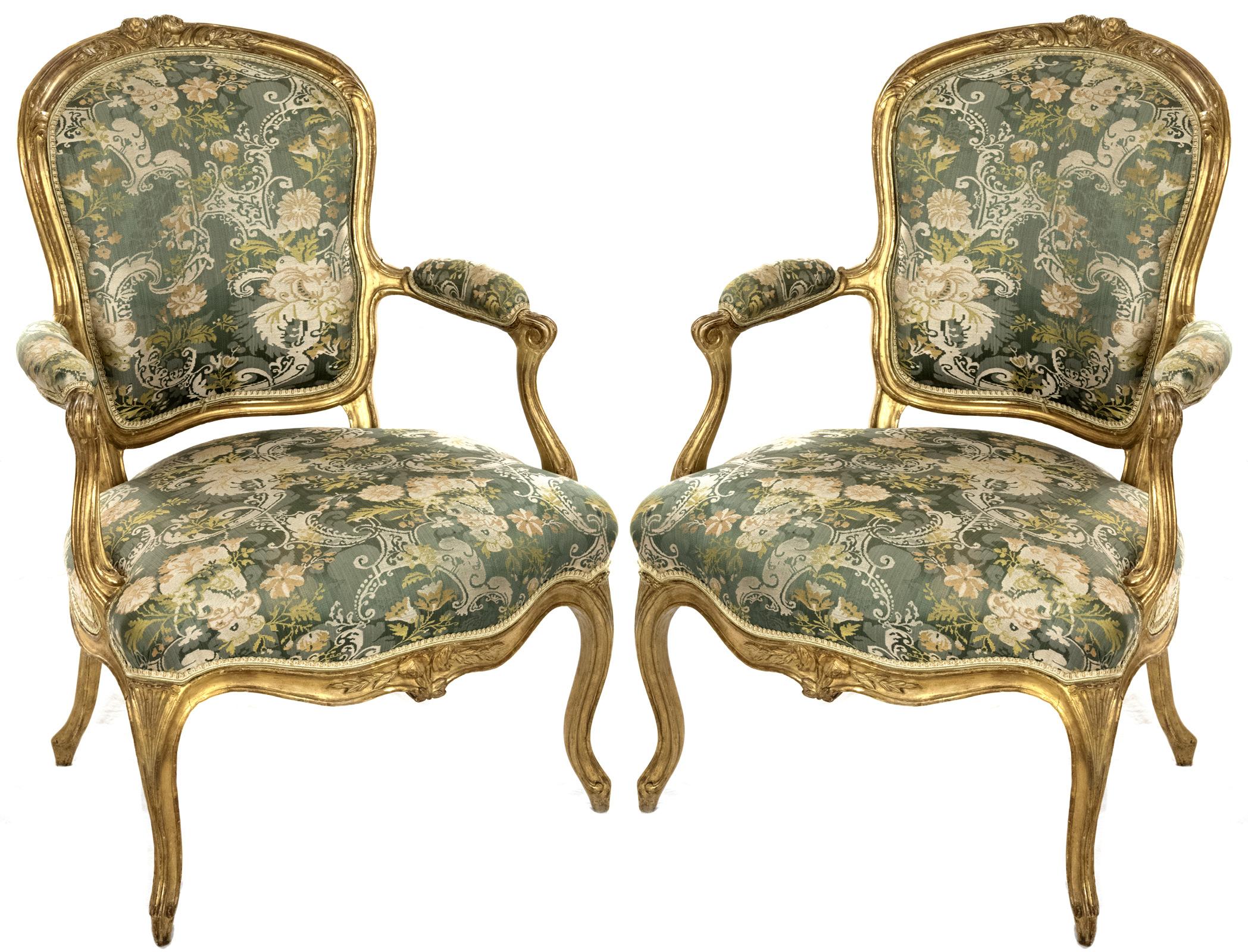 A pair of mid-18th century, circa 1755, Louis XV giltwood armchairs by Jean-Baptiste Lebas (French, 1729-after 1795), the cartouche-form backrest and broad seat are upholstered in a floral needlepoint pattern, with arms with conforming manchettes.