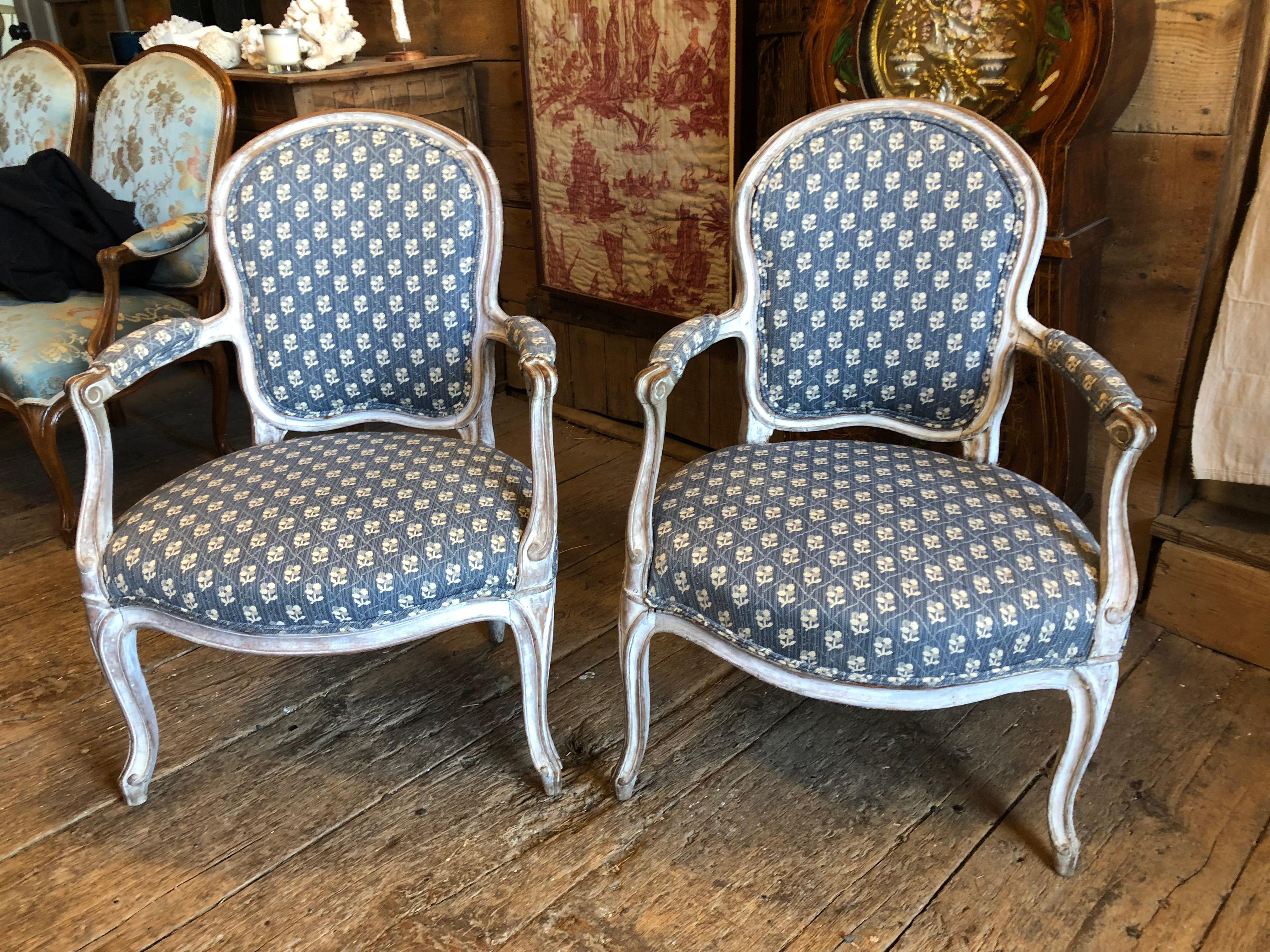 A pair of French Louis XV period fauteuils en cabriolet, circa 1760, in whitewashed frames upholstered in blue and white fabric.
 