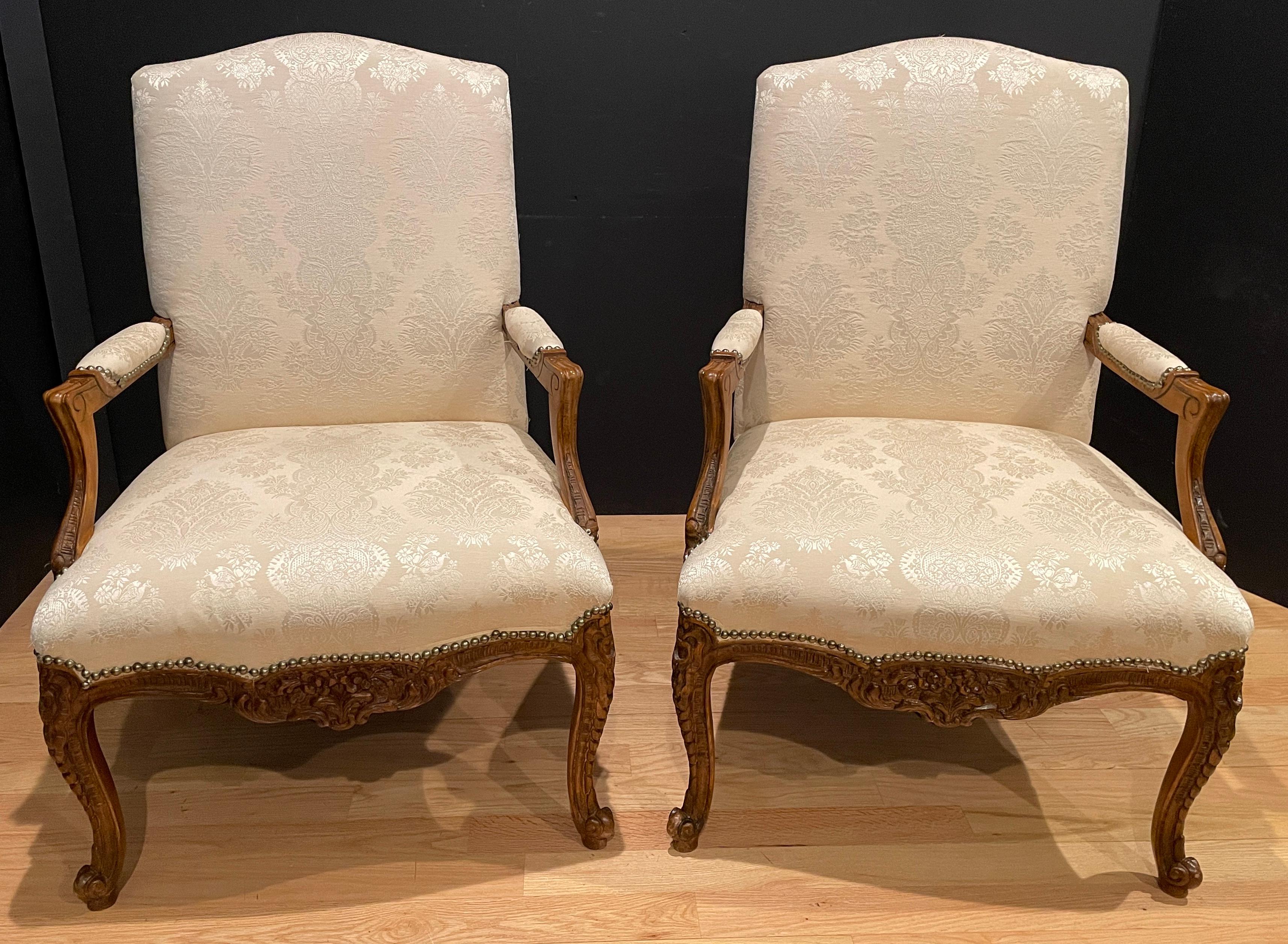 Pair of hand carved walnut oversized vintage Louis XV style fauteuil armchairs. Beautifully upholstered in off-white damask with nail head details.