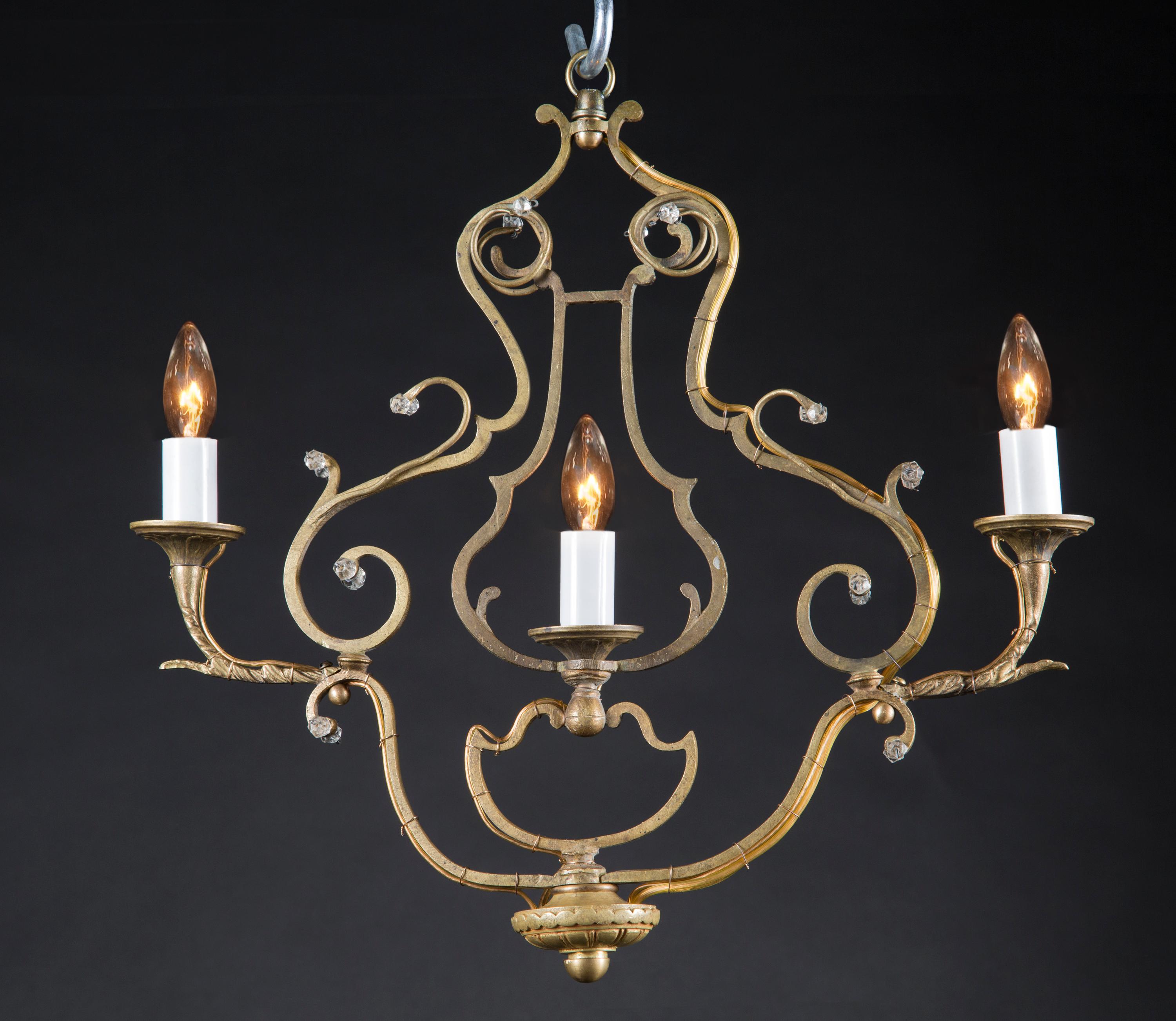 This unusual pair of antique French Louis XV bronze chandeliers feature a linear design perfect for hallways. The three lights sit centrally, two outside and one inside a lyre shaped frame. Slight crystal work is featured on the Louis XV style