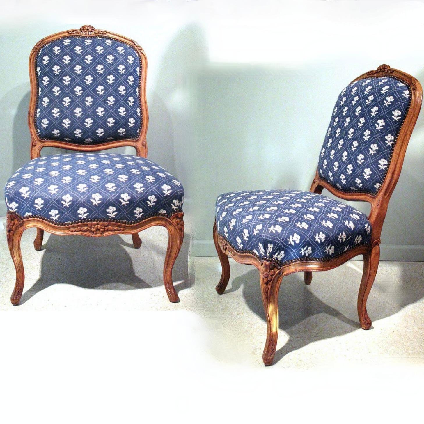 A pair of period mid 18th century French chairs, the natural beechwood frames of sturdy and comfortable proportions. Serpentine lines are well balanced throughout the back and seat, punctuated by traditional floral and foliate carving. In