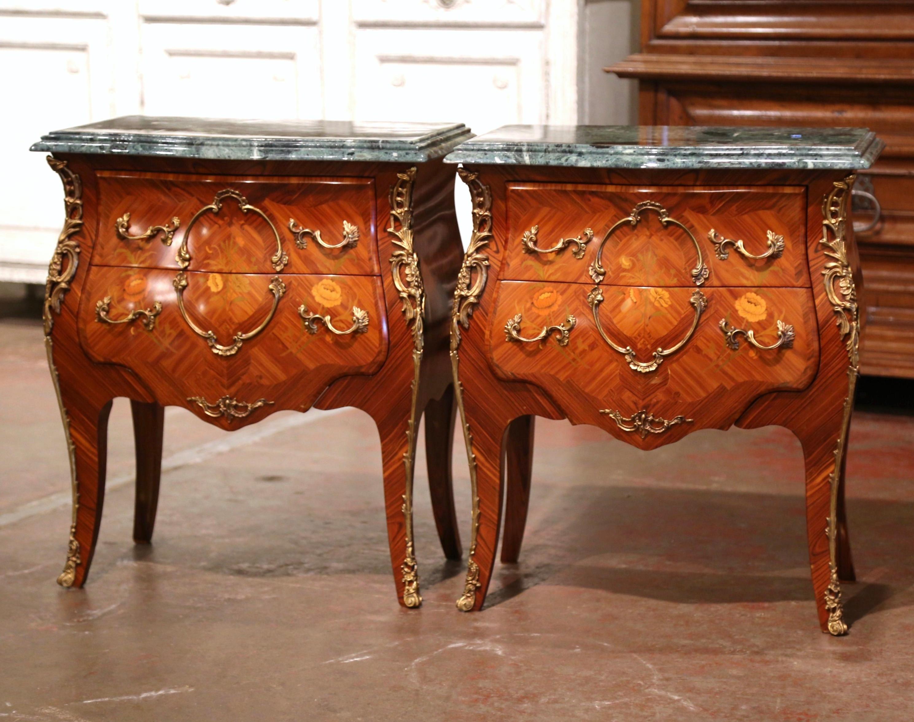 These elegant two-drawer bedside tables were created in France, circa 1980. Bombe in shape on all three sides, the petite chests stand on cabriole legs ending with bronze sabot feet decorated with acanthus leaves over a scalloped apron embellished
