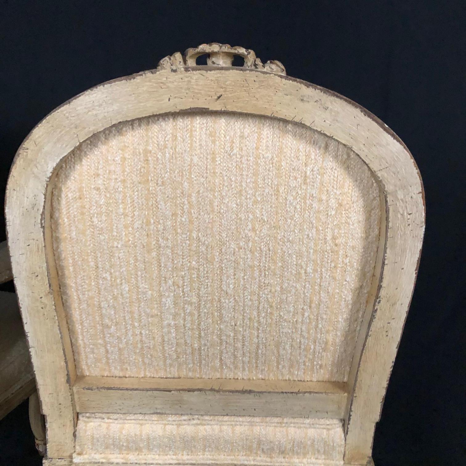  Pair of exquisite painted French bergère armchairs with ivory and cream paint and immaculate complementary upholstery, circa 1940s. Reupholstered in beautiful and tasteful textured ivory and cream material. Immaculate! 
arm height 25.5
#5248