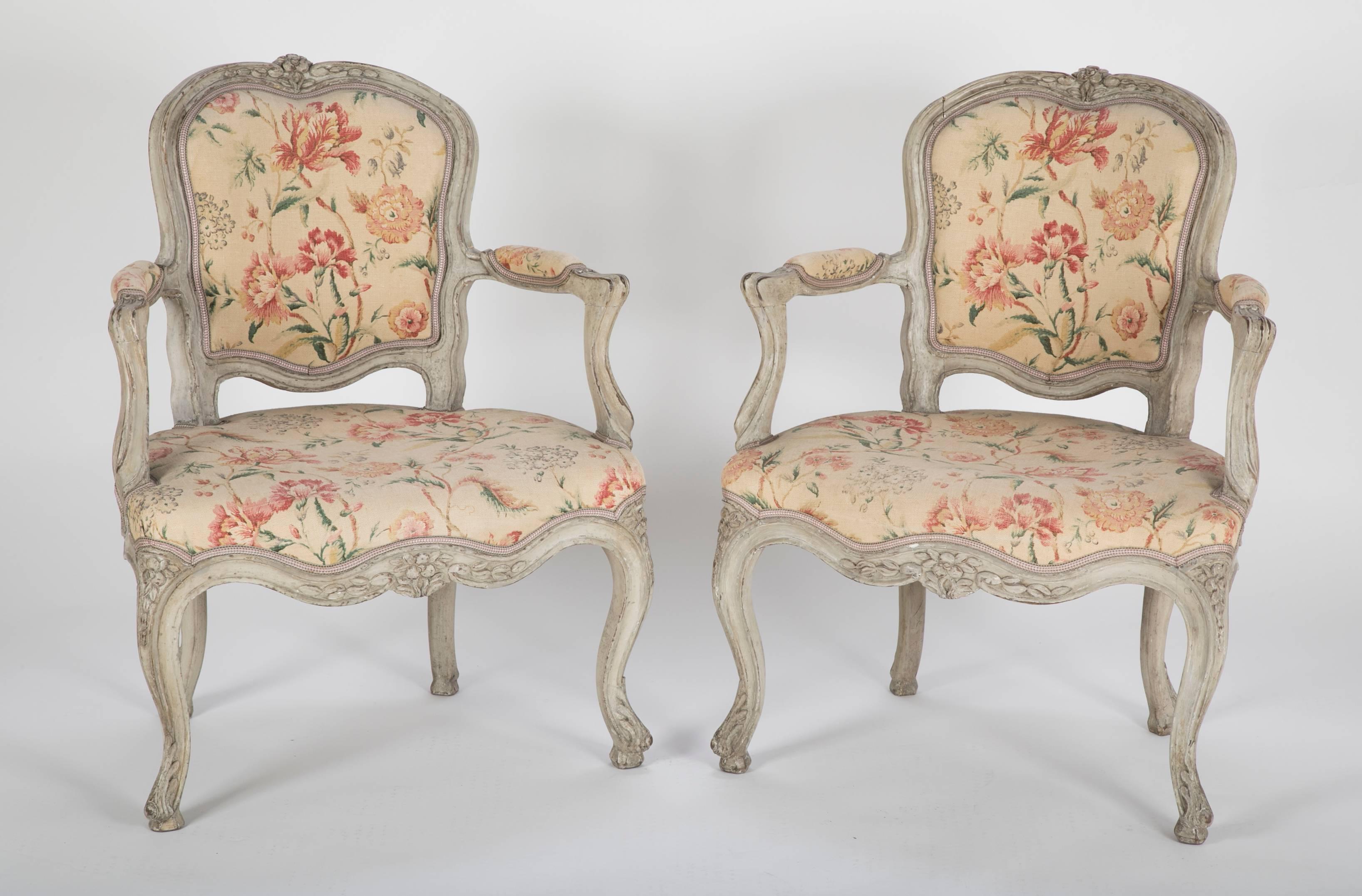 A pair of Louis XV beechwood open armchairs (fauteuils) with robust country carving.