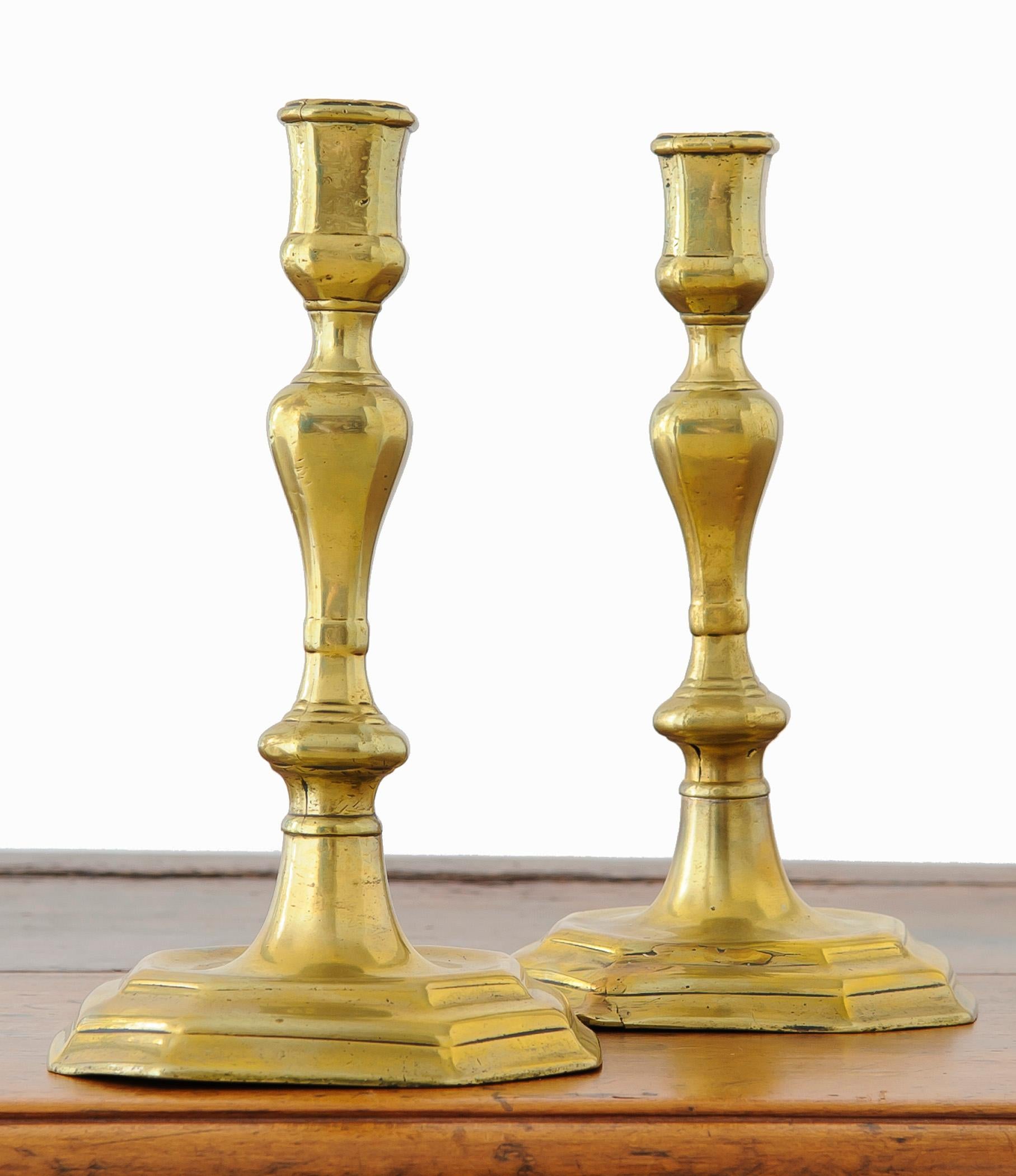 Pair of Louis XV, Regence period, bronze candlesticks.  The candlesticks have a shell and asymmetrical rocaille motif.  The candlestick base is a soft cornered hexagon with the shell and curl repeated.  The candlesticks are of heavy weight.   