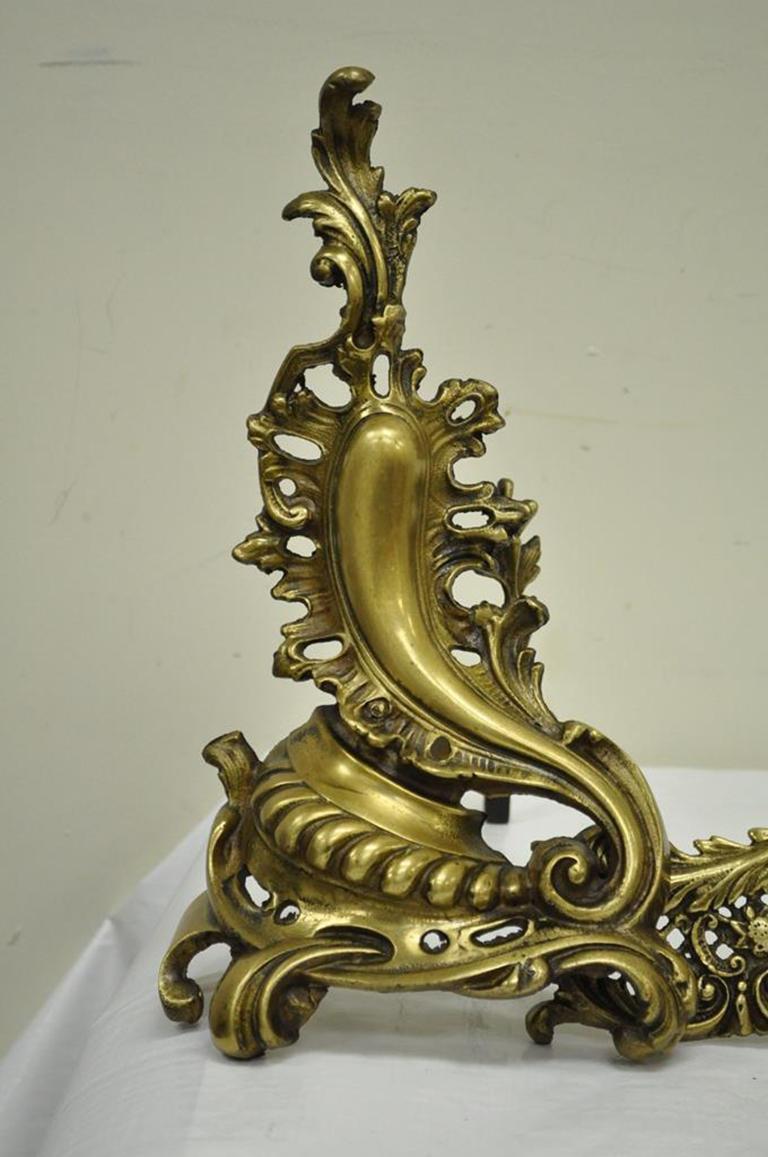 Pair of beautiful antique French Rococo style bronze or brass andirons and attached fender. The set features a great sculptural acanthus form, unique leaf form finials, and an openwork lattice fender, circa early to mid-1900s. Measurements: 16.5