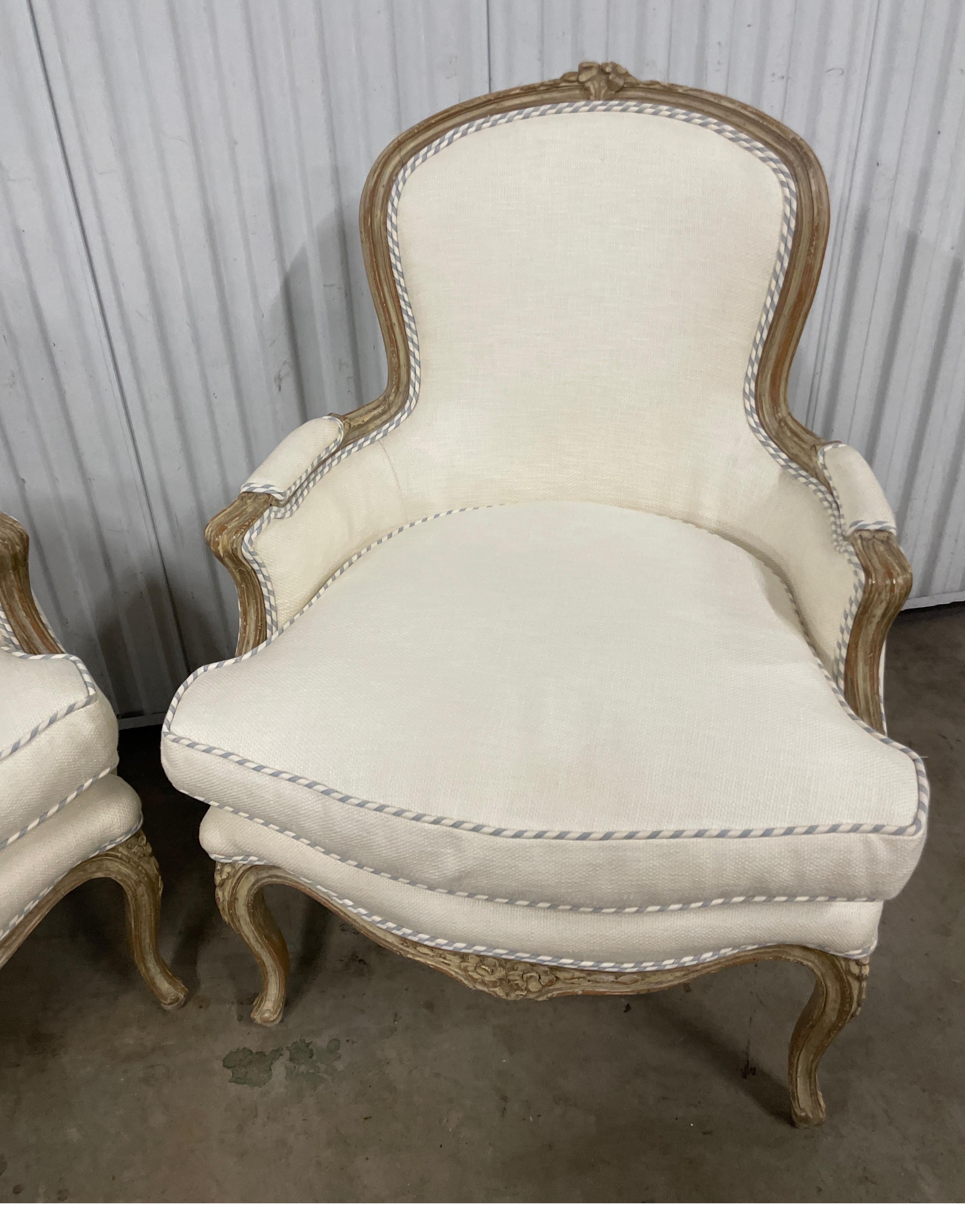 Very chic pair of 19th century French Bergere chairs upholstered in an off white cotton / linen fabric with blue & white ticking welt & backs. Frames have a light whitewash finish.