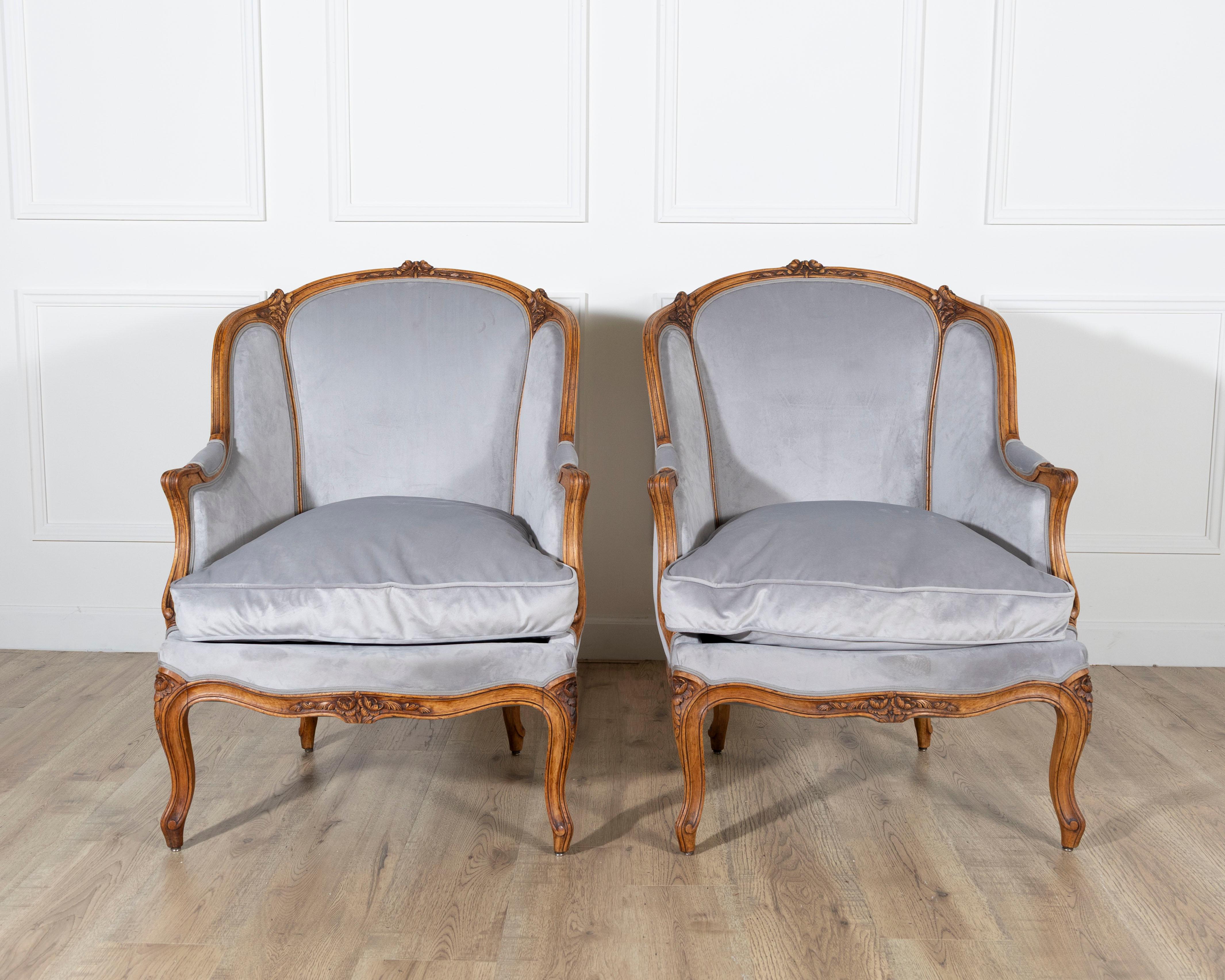 A graceful pair of Louis XV-style gondola armchairs from the 20th century, crafted in beechwood and newly upholstered for modern comfort. The carved wooden frames display the elegant curves and floral motifs characteristic of the Rococo aesthetic,