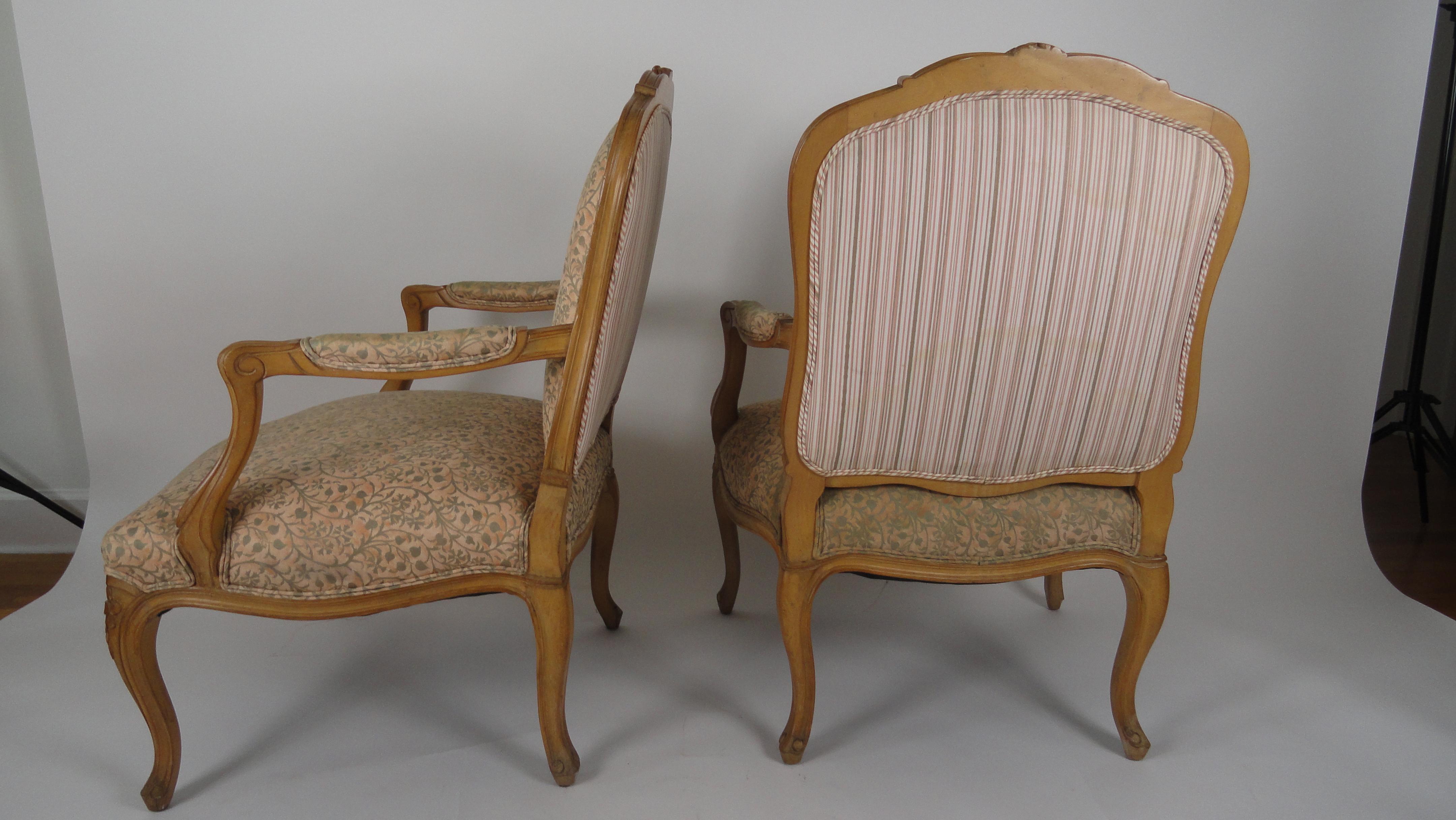 Pair of French open armchairs in the French Louis XV style. Cartouche shaped padded backs, padded down scrolled arms. Serpentine upholstered seats with curved detail on cabriole legs. Beautiful hand carving. Covered in Fortuny.