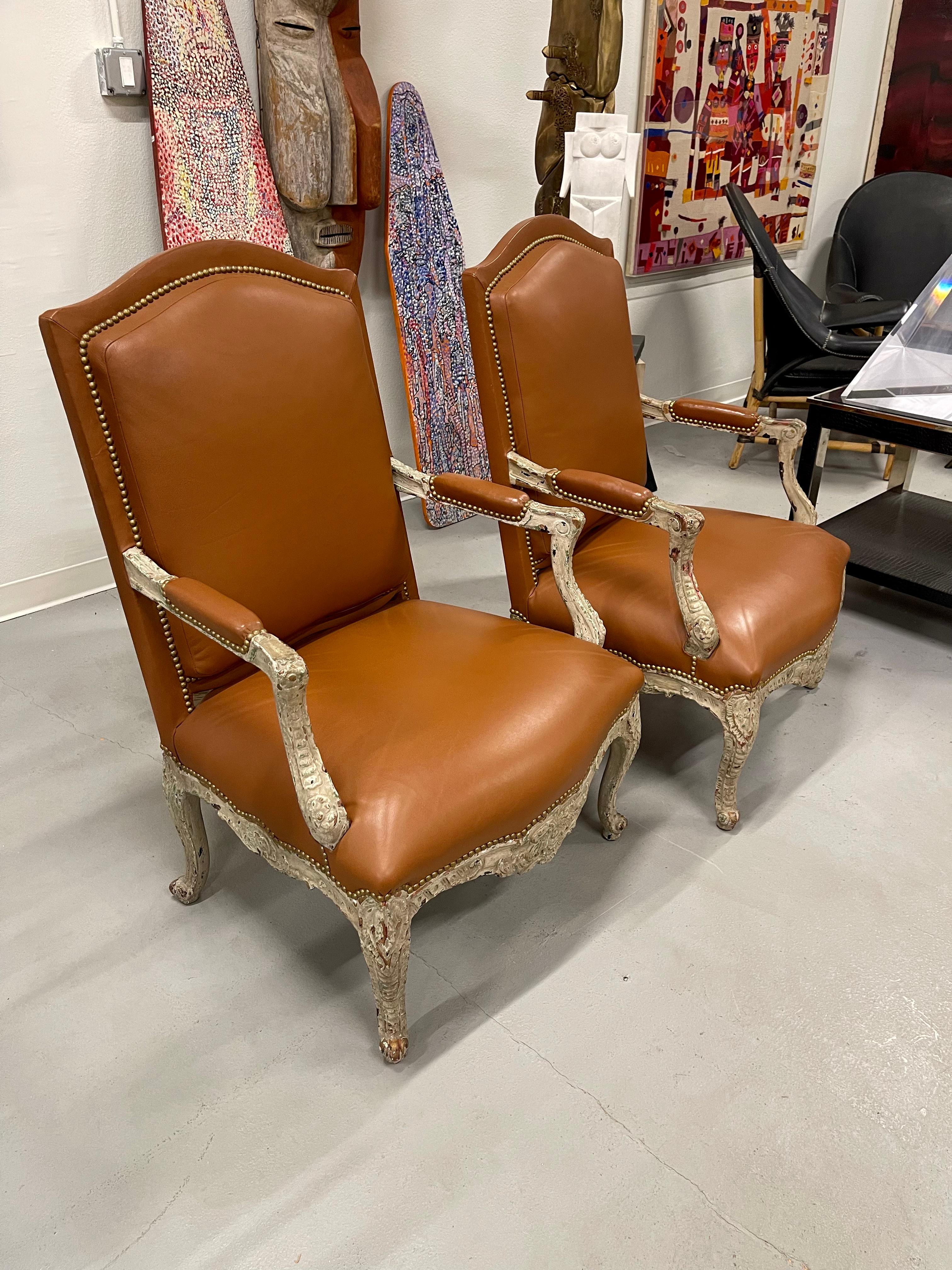 A beautiful pair of 19th century Louis XV Bergeres upholstered in Leather and woven grasscloth. The painted surfaces have quite a few layers of chippy paint, which looks wonderful. The nailhead detail is nice. The leather is in excellent condition.