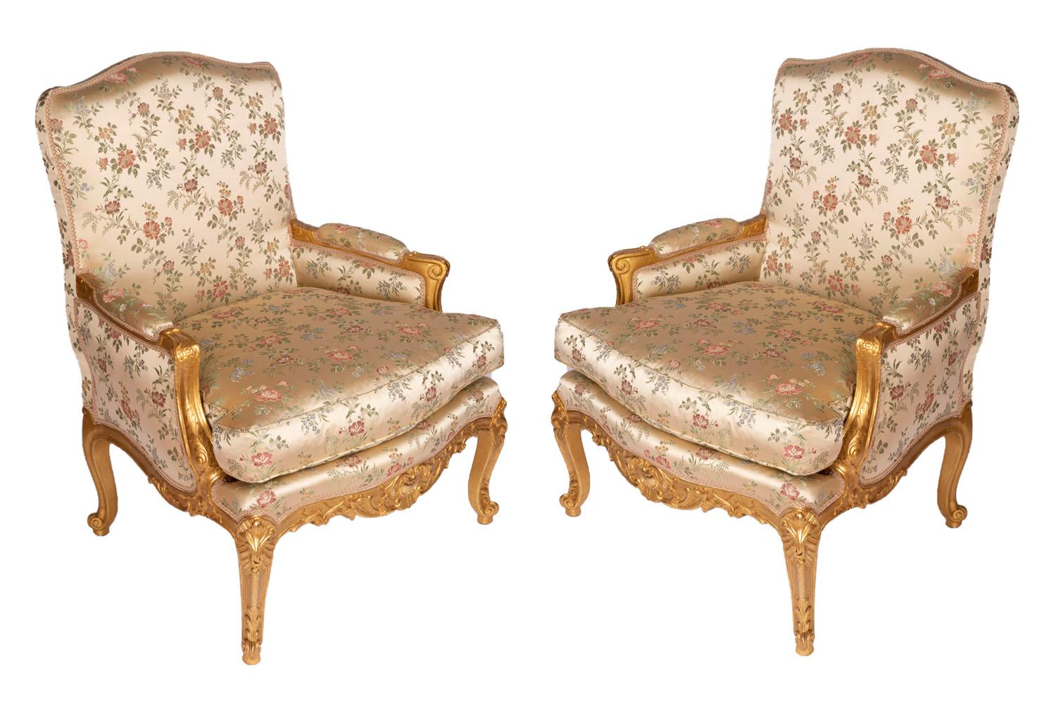 Pair of Louis XV style bergères with a flat back in giltwood, standing on four cabriole legs with an carved decor of acanthus leaves and scrolls. Apron slightly bulged with a carved decor of acanthus leaves, cartouche and shell. Arm supports behind