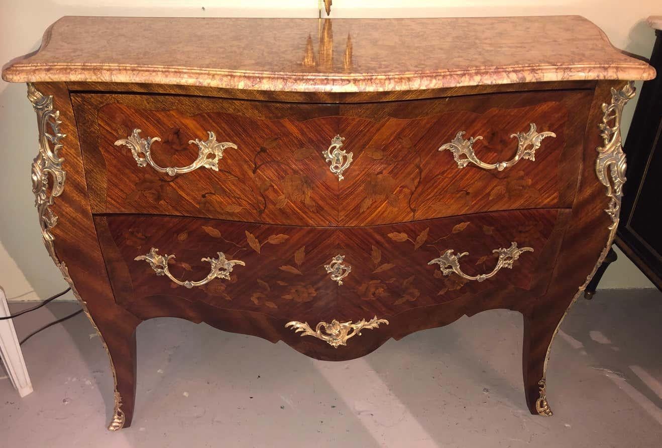 A pair of Louis XV style bombe bronze mounted commodes with rouge marble tops. Each of these large and impressive commodes or nightstands is simply stunning. The sides and front all having floral inlays of kings-wood and satinwood with walnut on oak