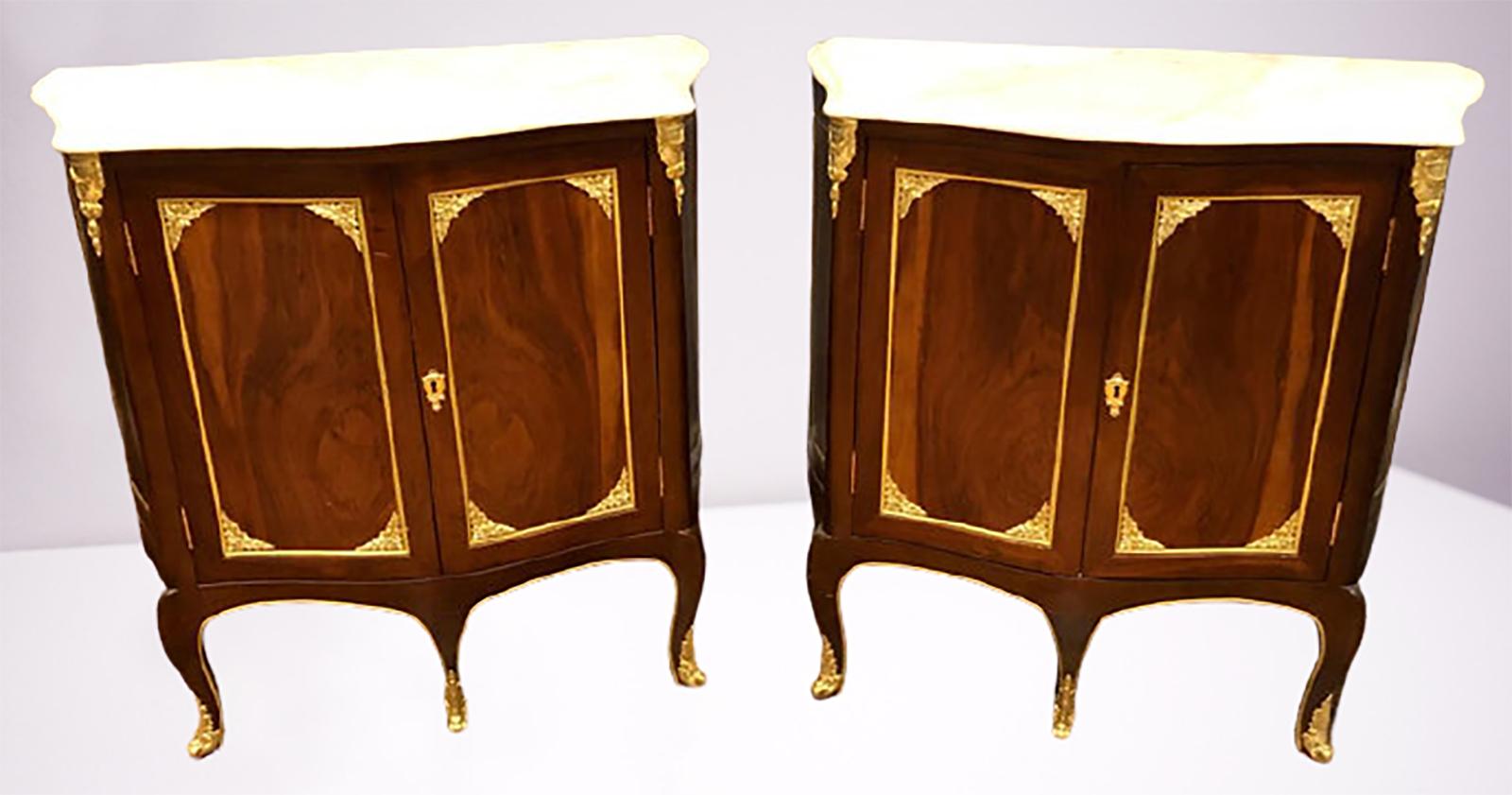 Pair of Louis XV Style cabinets commodes or nightstands. The pair having oak shelved interiors with full locks. The fronts a Fine mahogany finish with full bronze mounts throughout. Each supporting a white marble top.