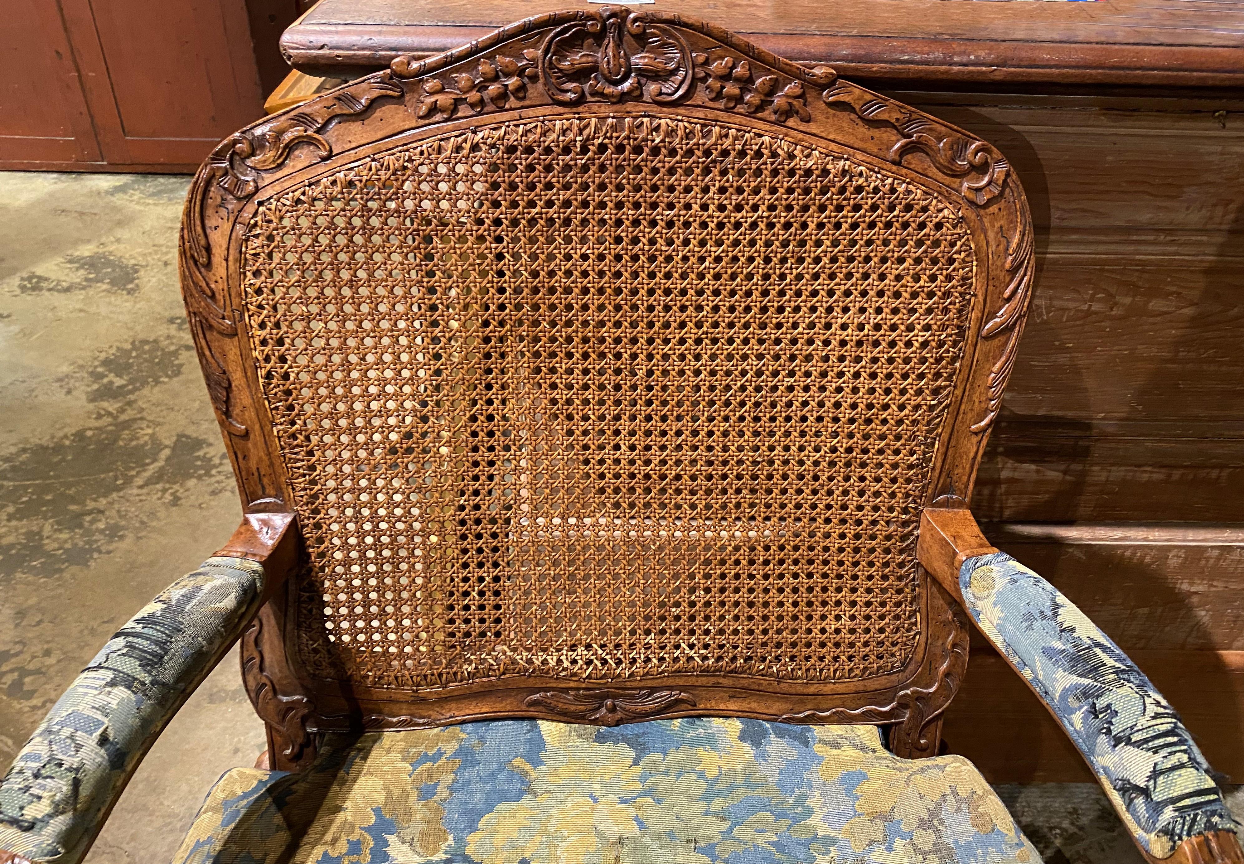 A fine pair of Louis XV caned fruitwood fauteuils or armchairs with foliate carved crests, arms, and legs, custom upholstered arms and removable upholstered cushions. This pair dates to the 19th century with later upholstery, great overall patina,