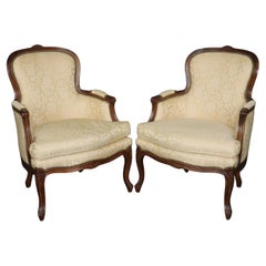 Antique Pair of Louis XV Style Carved Bergeres with Baker Upholstery and Nailhead Trim